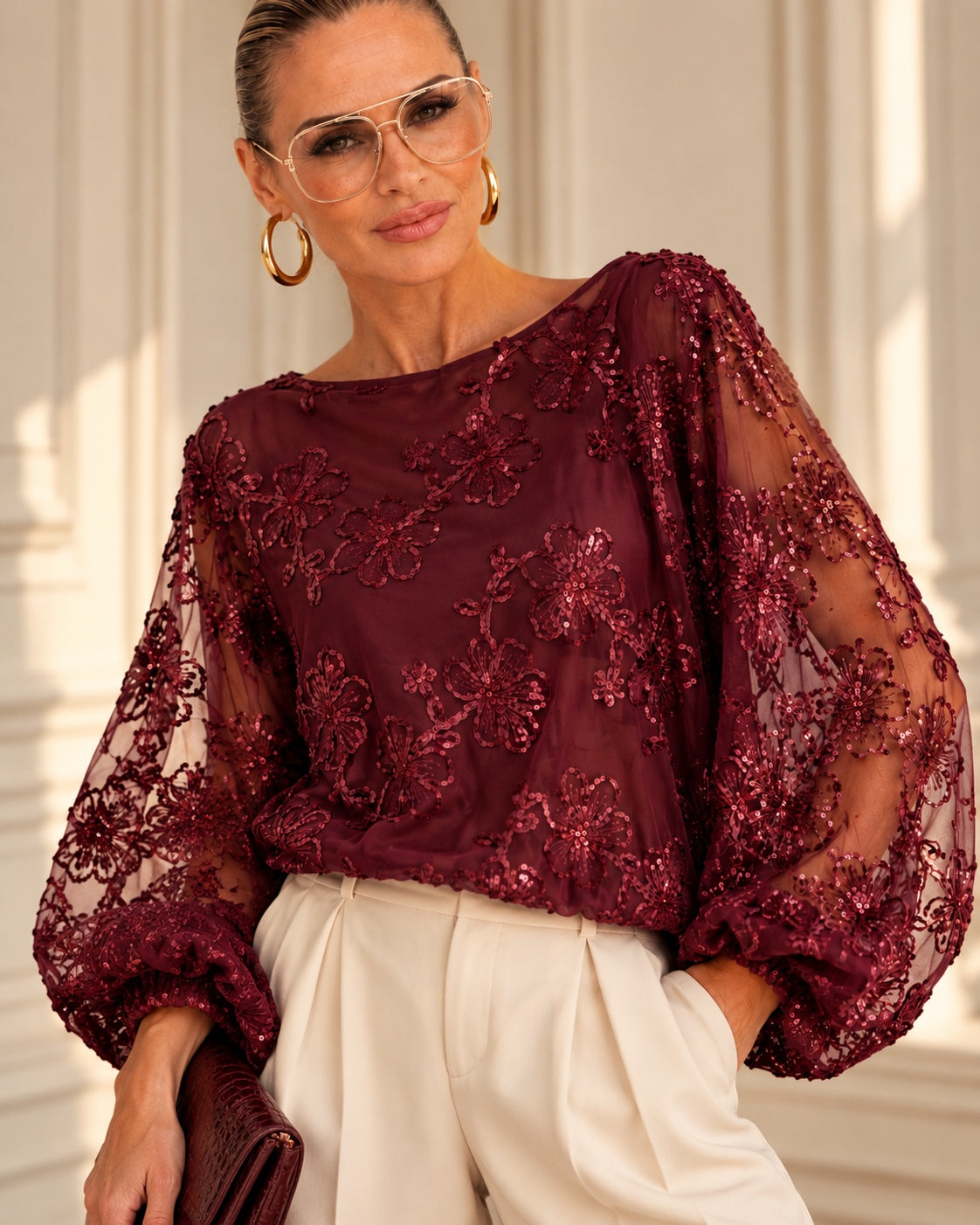 Model in burgunderfarbener Midnight Bloom Bluse mit Paillettenblüten und transparenten Fledermausärmeln