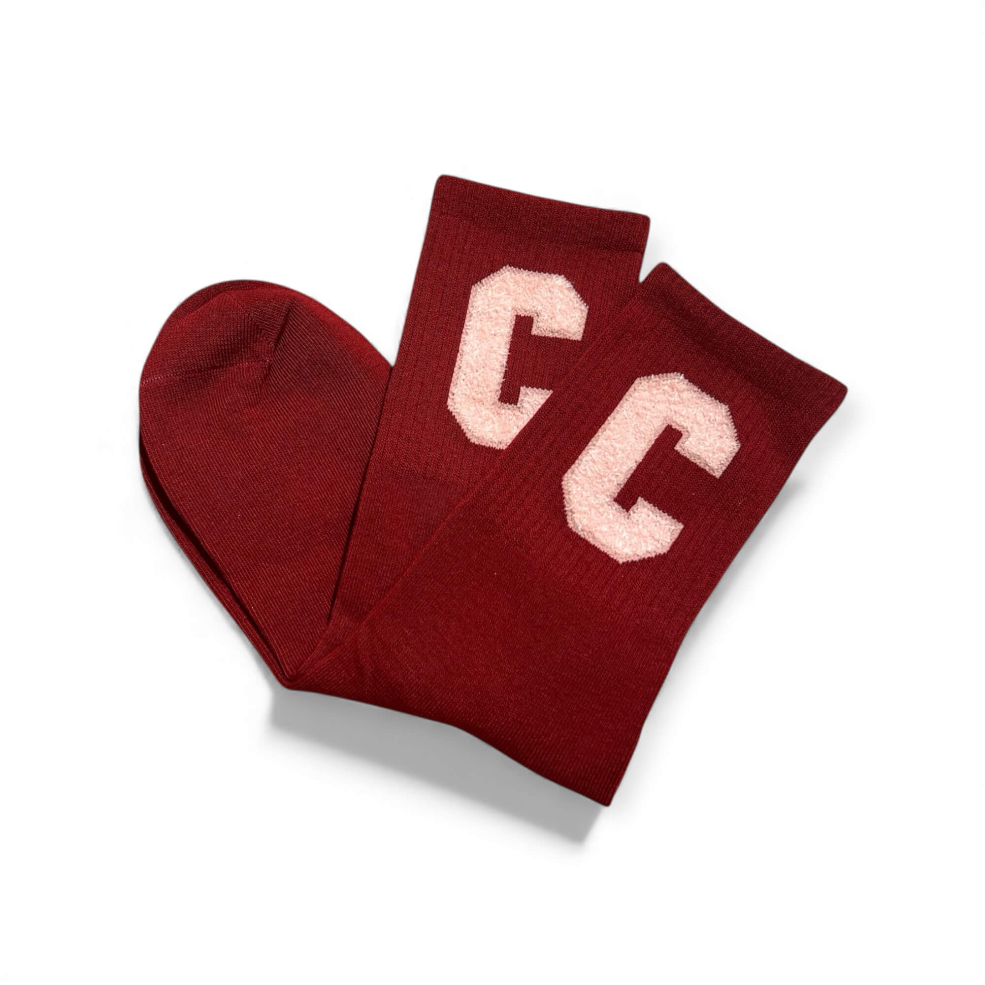 Braune kurze Socken aus weichem Strick, flach liegend fotografiert, mit zwei rosa „C“-Buchstaben auf dem Schaft. Die Socken liegen leicht überkreuzt auf weißem Hintergrund.