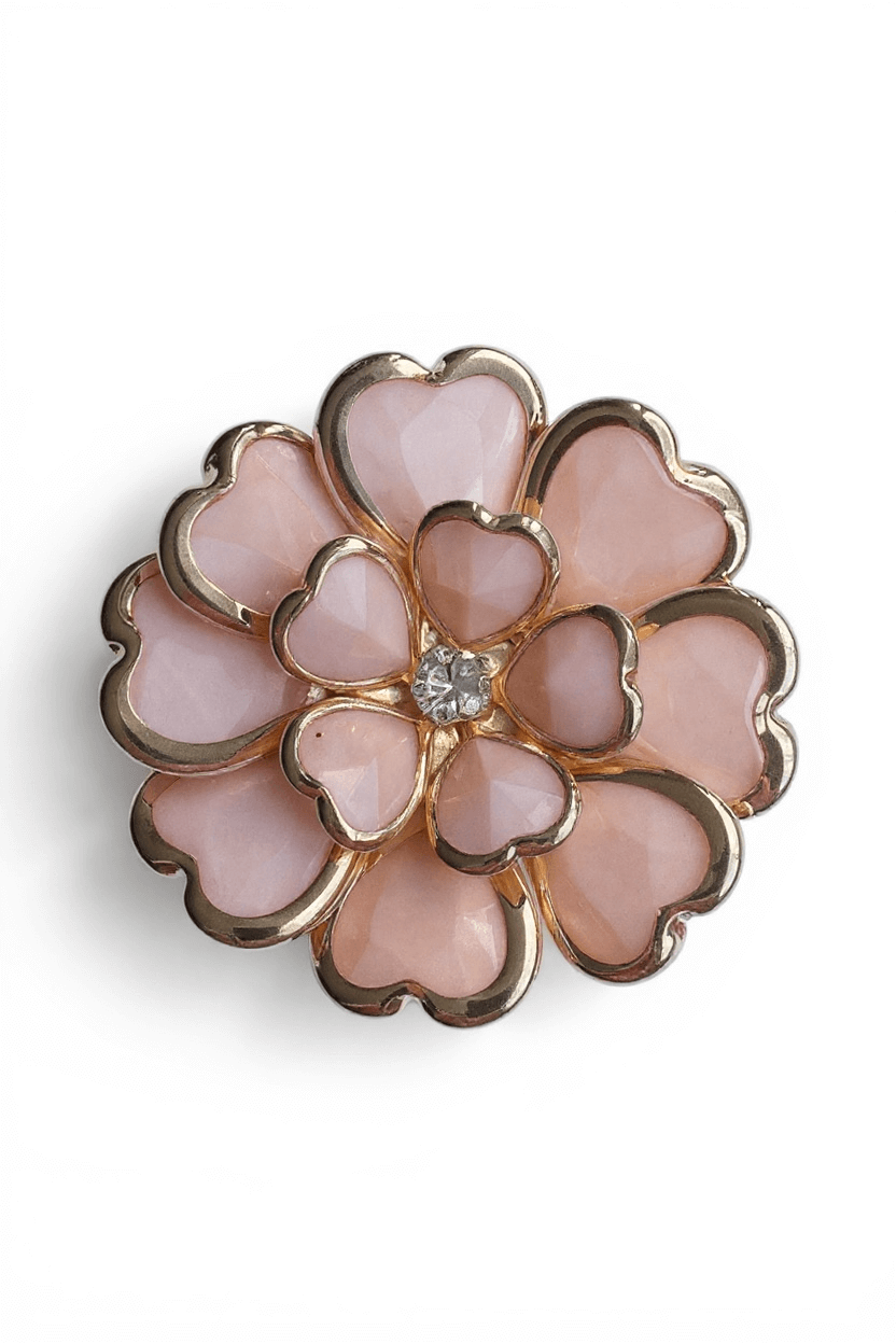 Blütenförmiger Schmuck-Clipper in Rosa mit herzförmigen, facettierten Steinelementen und goldfarbener Fassung, mittig ein transparenter Zierstein.