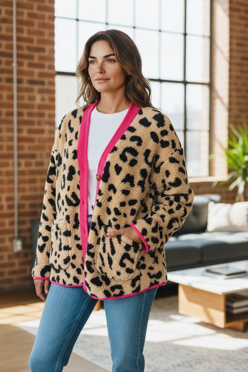 Frau trägt beige braune Leo Jacke mit pinken Details dazu eine Jeanshose fotografiert in einem hellen Zimmer.