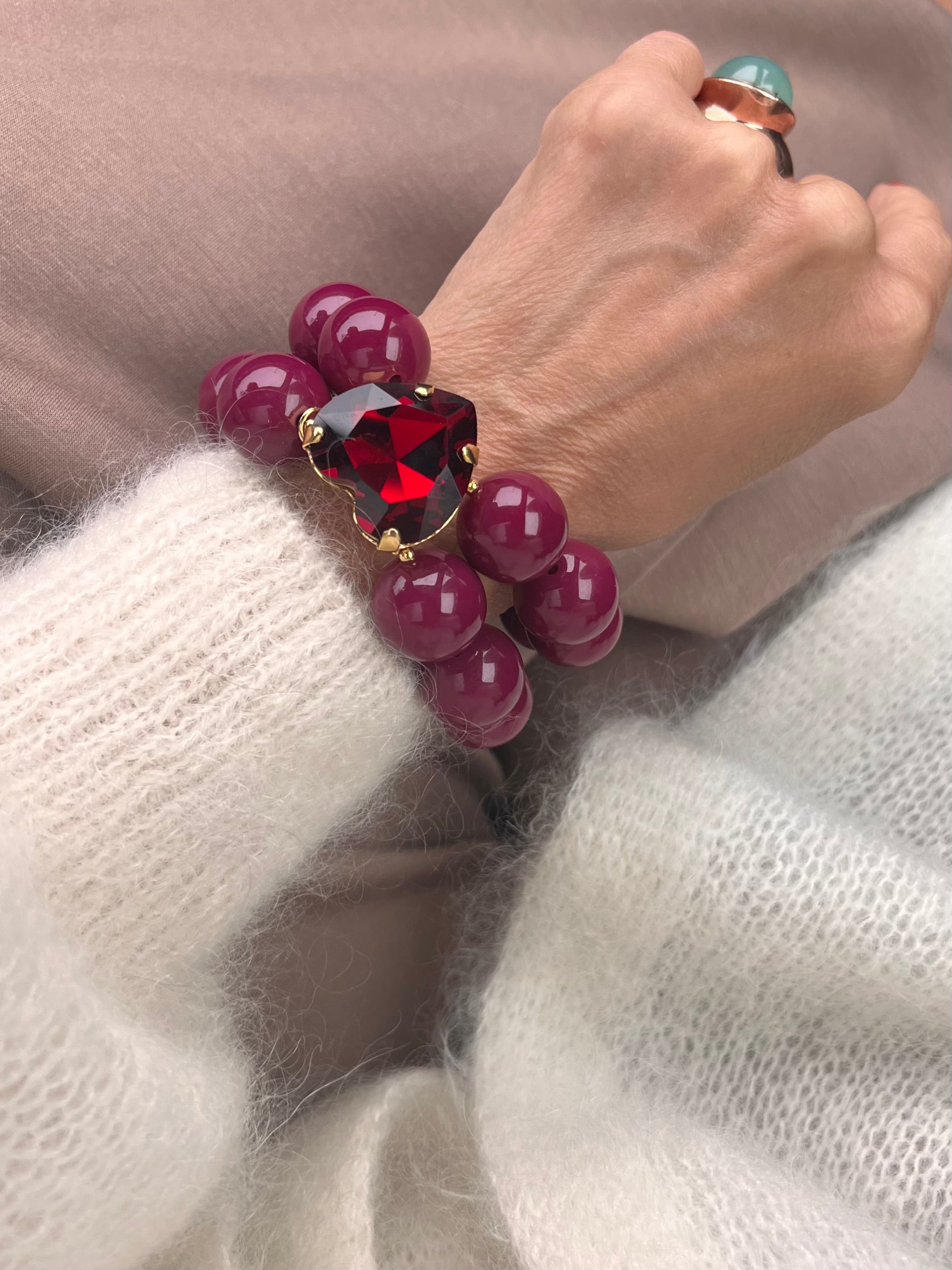 Armband in Burgundy mit großem Herzschmuckstein, und großem Ring. Am Handgelenk auf beigem Stoff fotografiert.