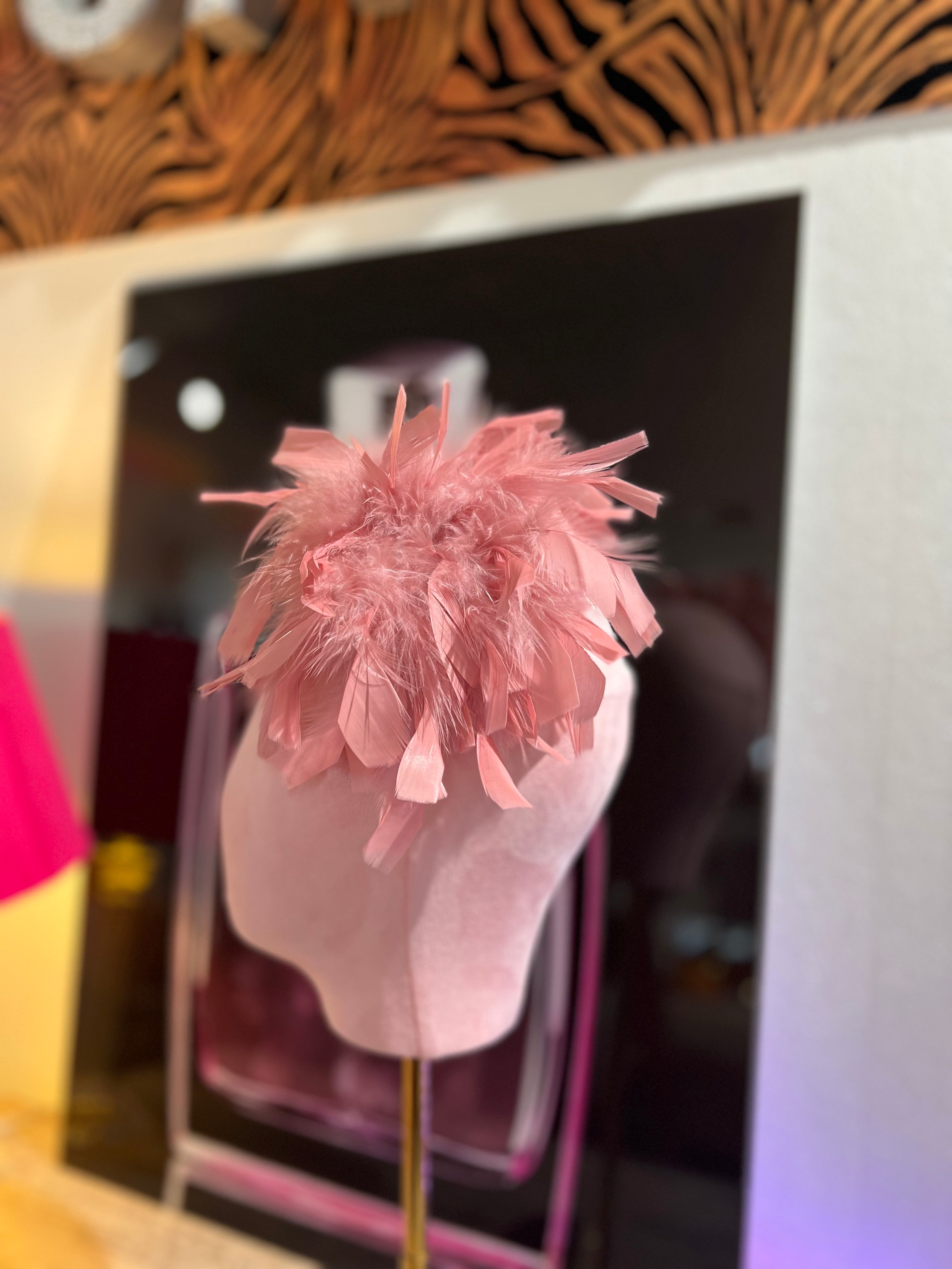Leuchtende Rosa Federbrosche, kunstvoll drapiert, präsentiert auf einem rosa Samt Kopf vor einer stilvollen Kulisse.