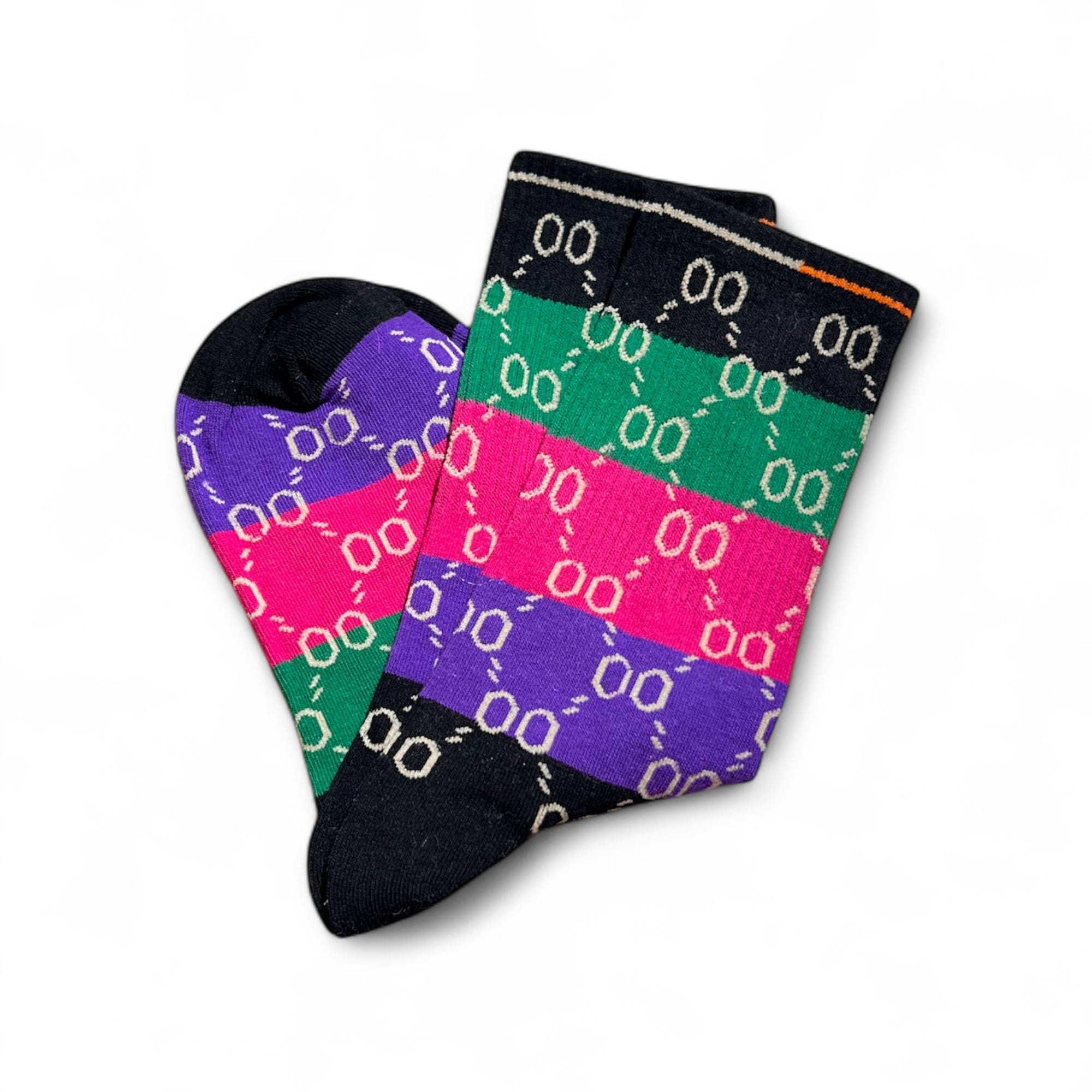 Bunte Socken mit Streifen in Schwarz Grün, Pink und Lila, flach nebeneinandergelegt auf weißem Hintergrund.