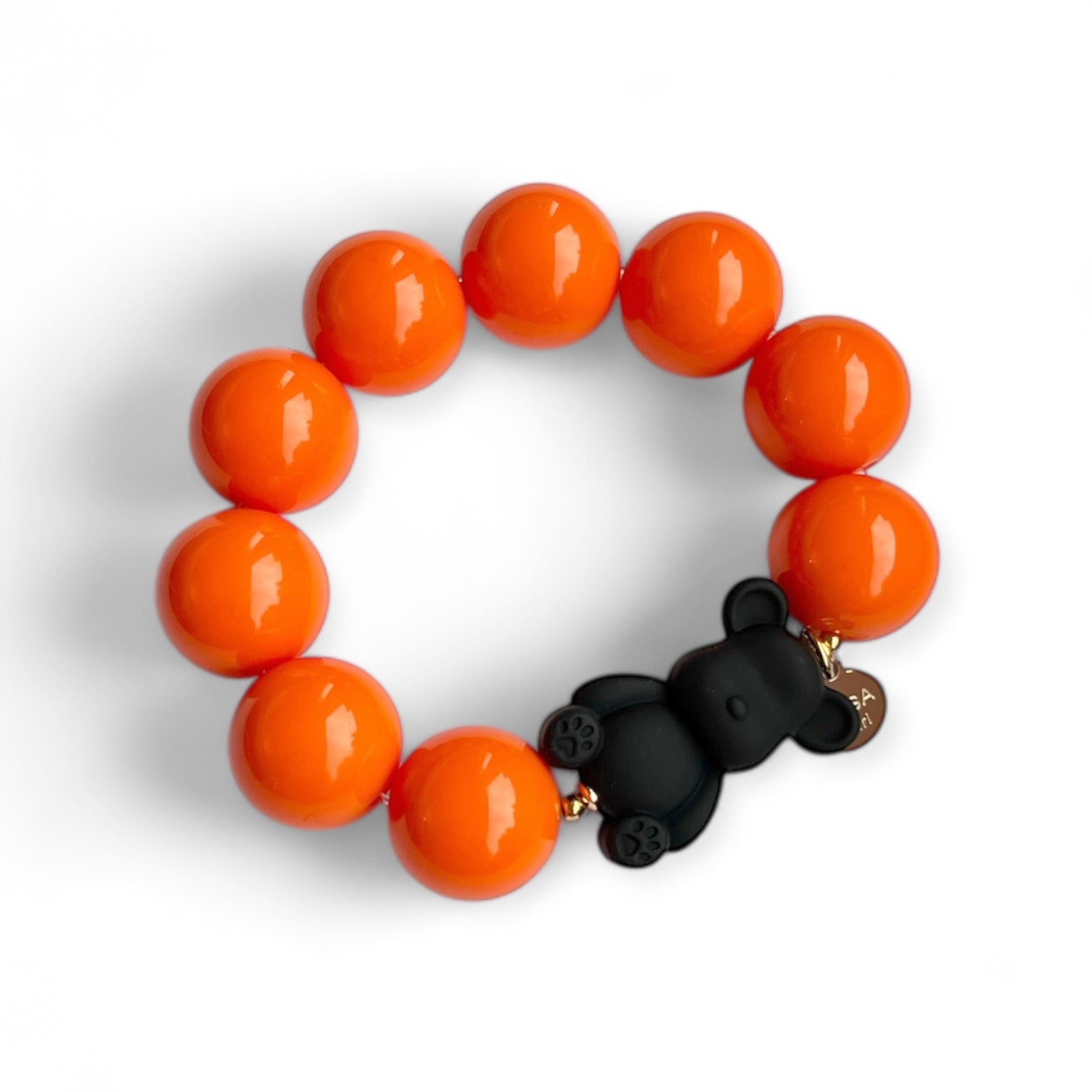 Armband aus orangefarbenen Kunstharzperlen mit einem kleinen schwarzen Bärenelement, handgefertigt von Casapari auf weißem Hintergrund.