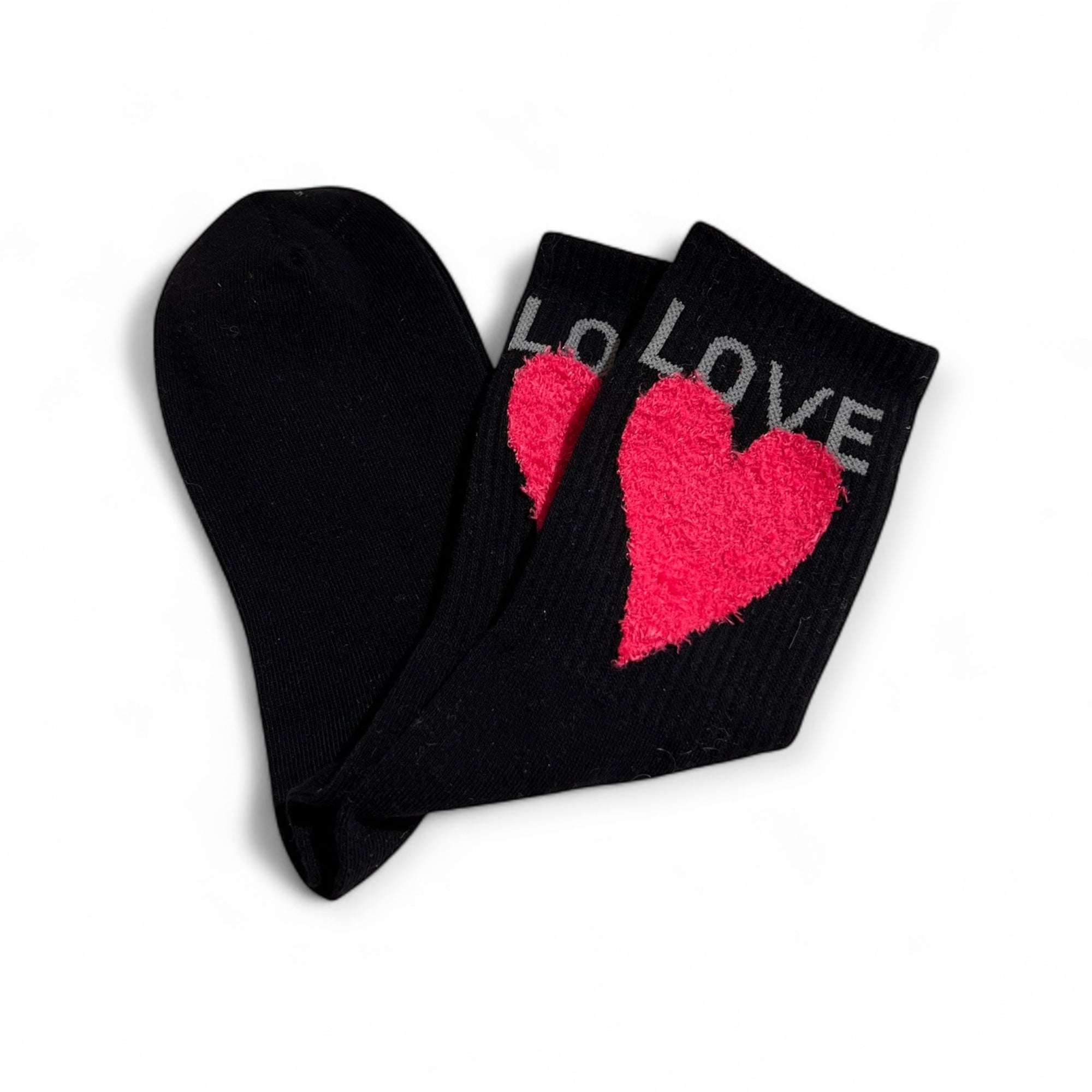 Schwarze Strümpfe mit pinkfarbenem Herzmotiv und dem Schriftzug LOVE am Bund. Flauschige Struktur auf dem herz, flach liegend auf weißem Hintergrund.