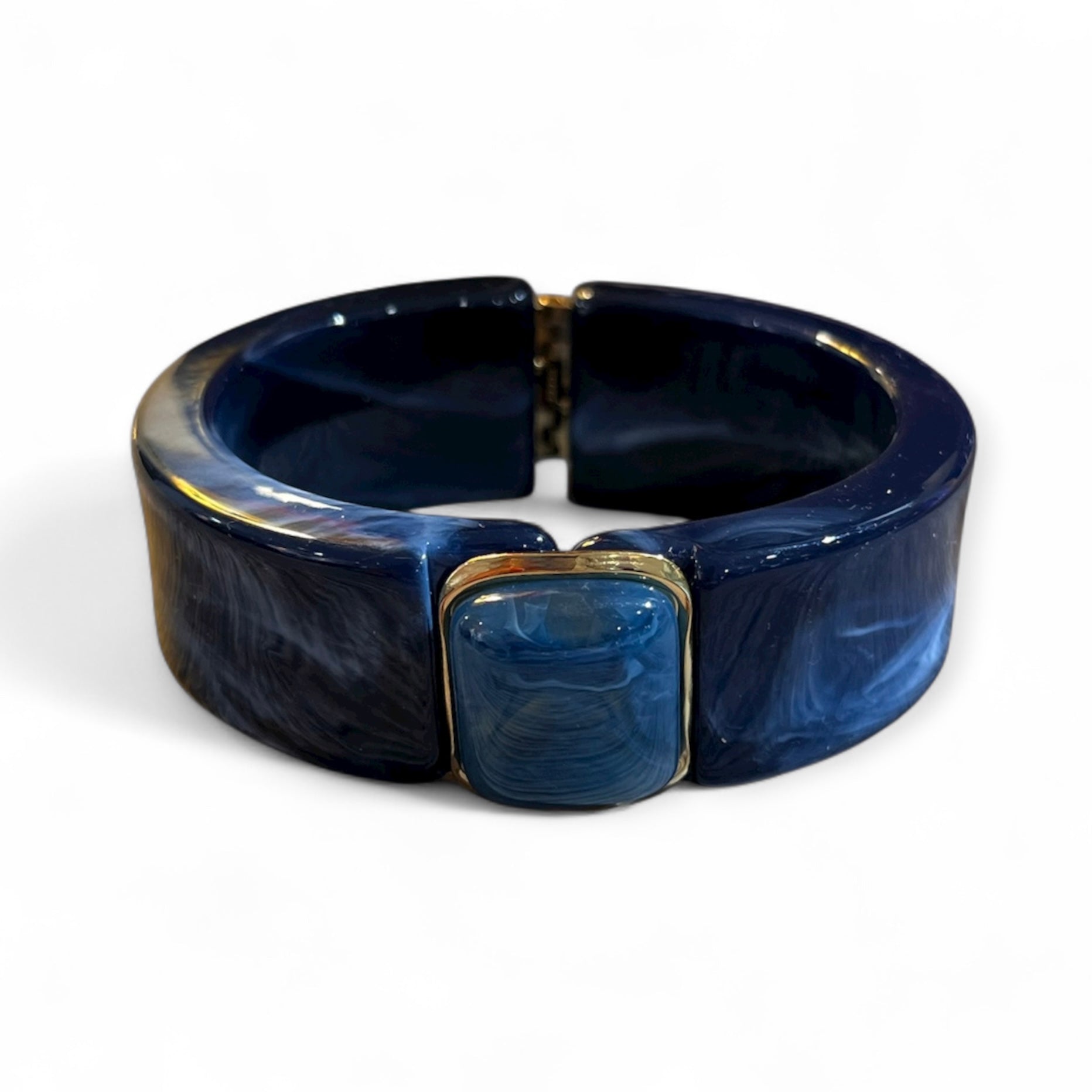 Klapp Armreif aus marmoriertem Kunstharz in tiefem Dunkelblau mit goldfarbenen Details und eingefasstem Schmuckstein.