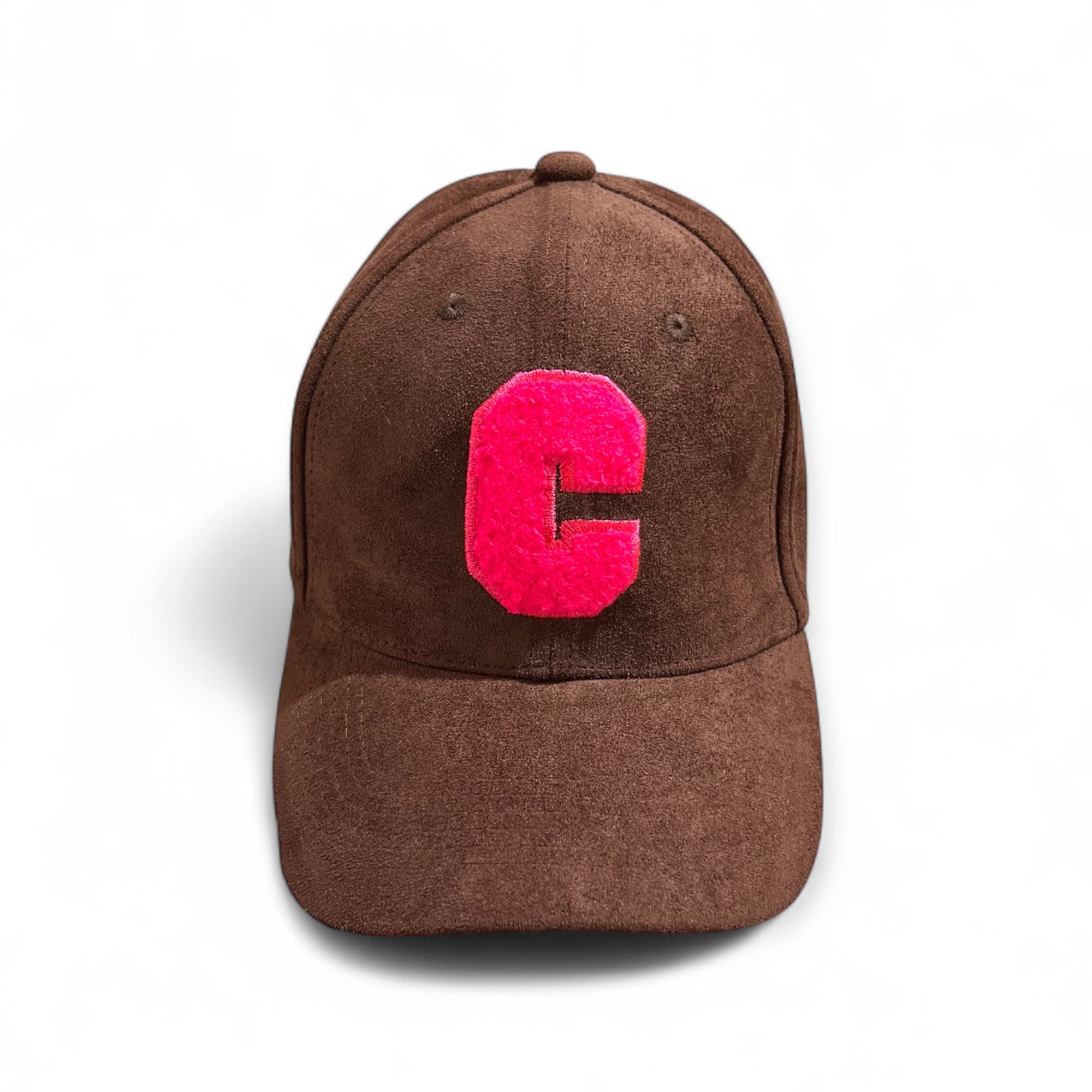 Braune Velours-Cap mit großem pinkem Buchstaben C auf der Vorderseite, fotografiert auf weißem Hintergrund.