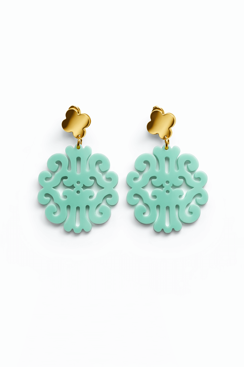 Paar hängende Ohrringe mit goldfarbenem Kleeblatt-Stecker und mint ornamental durchbrochenem Anhänger vor weißem Hintergrund.