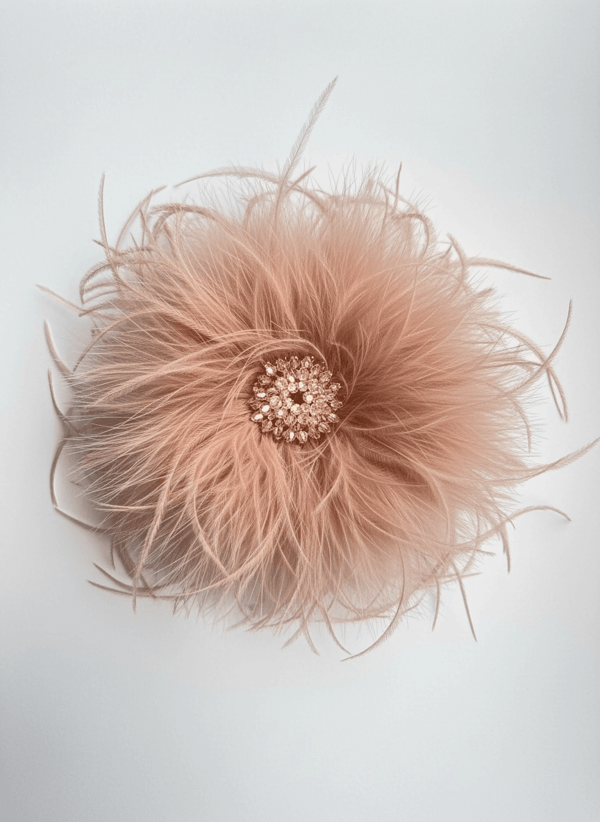 Federbrosche in zartem Rosé mit voluminösen Federn und mittigem Besatz aus Perlen und Strass, auf hellem Hintergrund.