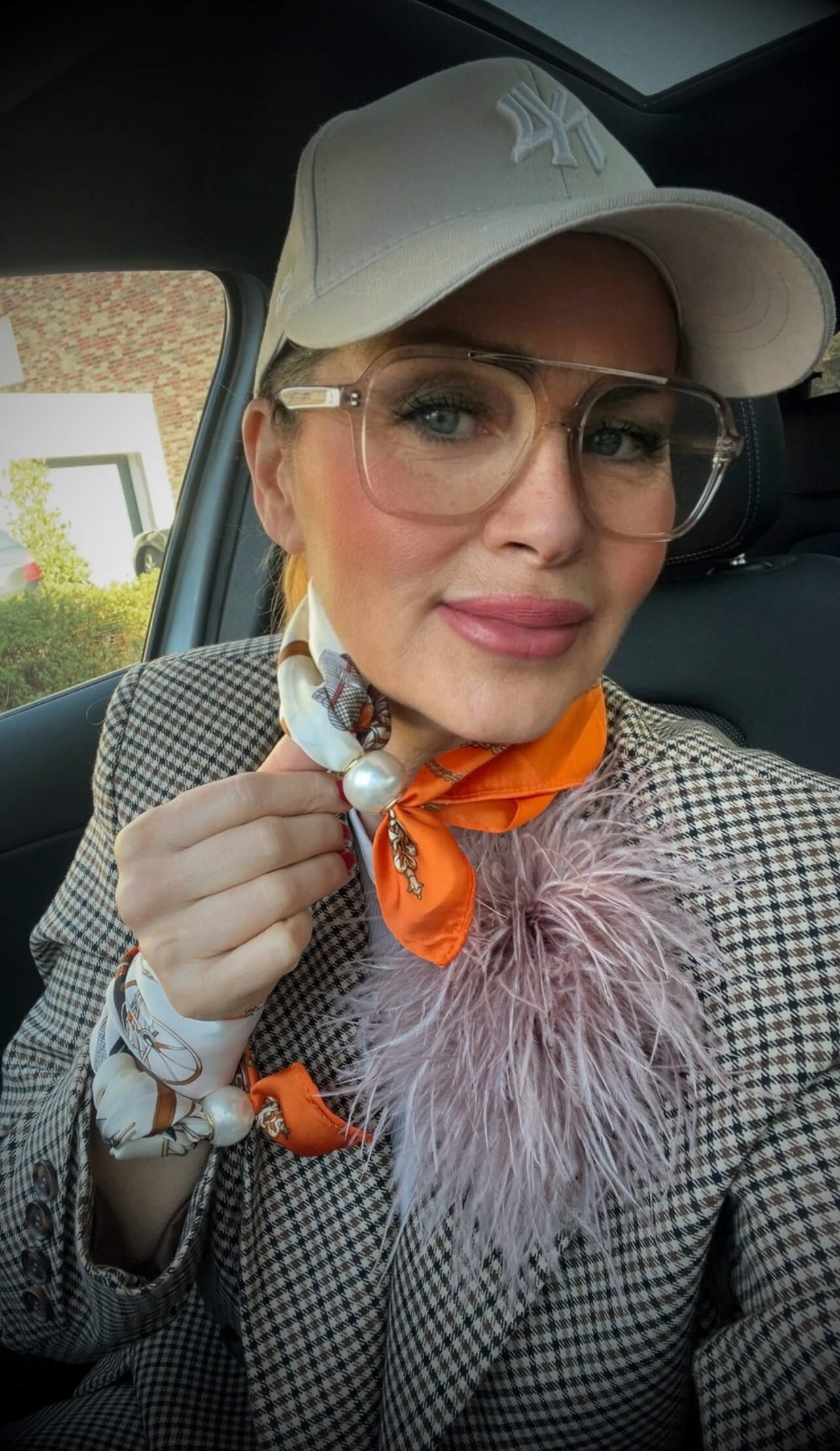 Frau trägt orange-weißes Tuch mit Perle als Halstuch, kombiniert mit Blazer