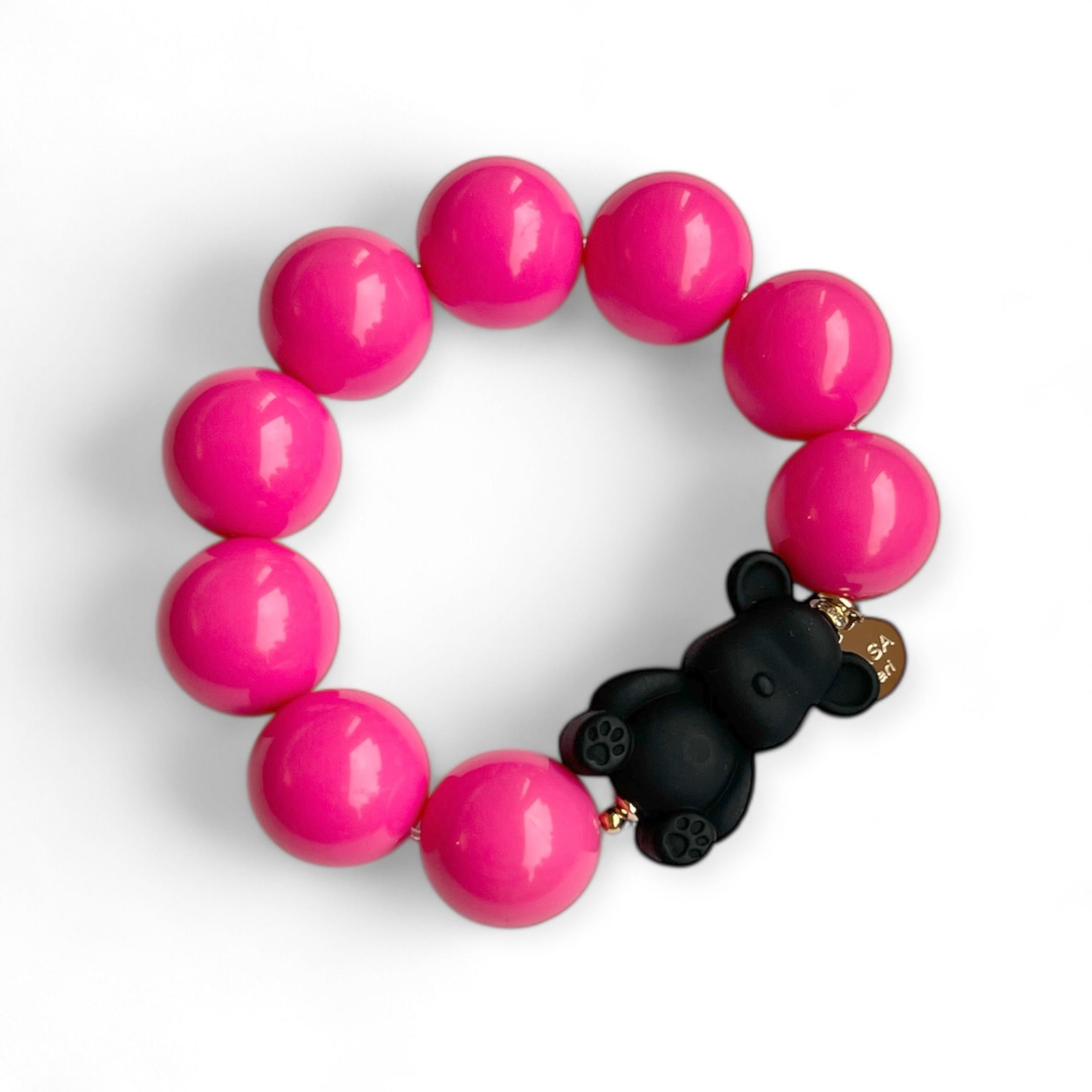 Armband aus fuchsiafarbenen Kunstharzperlen mit einem kleinen schwarzen Bärenelement, handgefertigt von Casapari auf weißem Hintergrund.