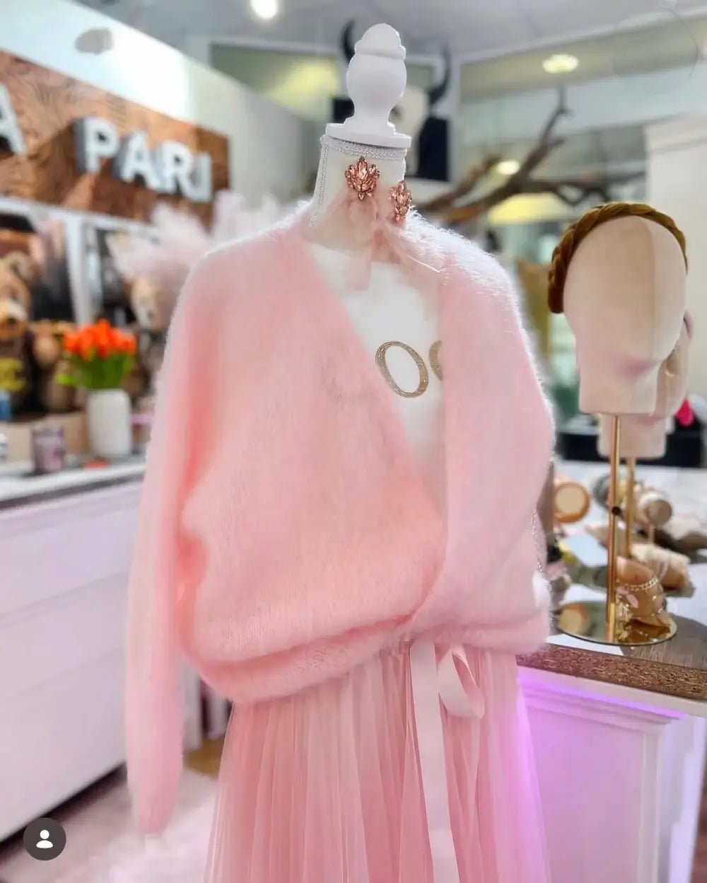 Rosa Kid-Mohair-Cardigan Rosé Cloud auf Schneiderbüste mit Wickeloptik und langen Ärmeln.“