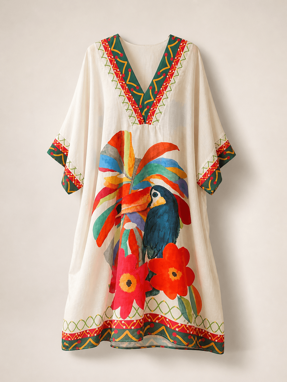 Beigefarbenes, locker geschnittenes Kaftan-Kleid mit V-Ausschnitt und kurzen weiten Ärmeln, auf einer unsichtbaren Puppe freigestellt; auffälliger Print mit Papagei, Blumen und bunten Zierelementen vorne sichtbar.
