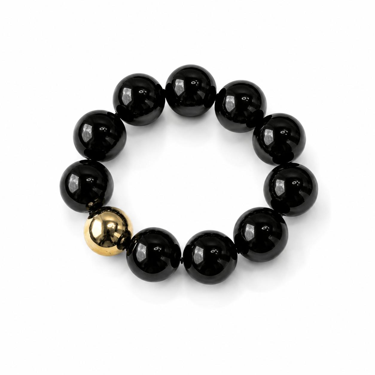 Schwarzes Armband mit einer goldenen Perle auf weißem Hintergrund fotografiert