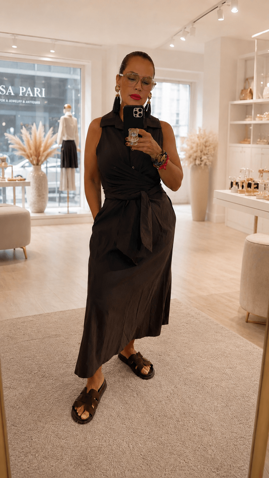 Frau steht in einer Boutique hat ein braunes Kleid an und mach ein Selfie