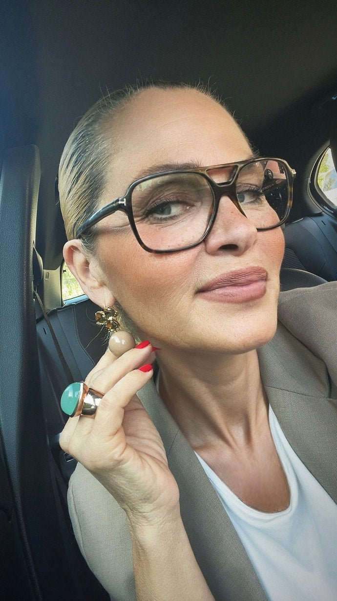 Frau mit eleganten Hänger Ohrringen in goldfarben, kombiniert mit großem Ring, stilvolle Accessoires.