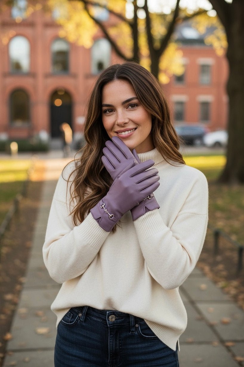 Frau trägt weißen Pulli mit einer Jeanshose. Und fliederfarbene Kunstleder Handschuhe.