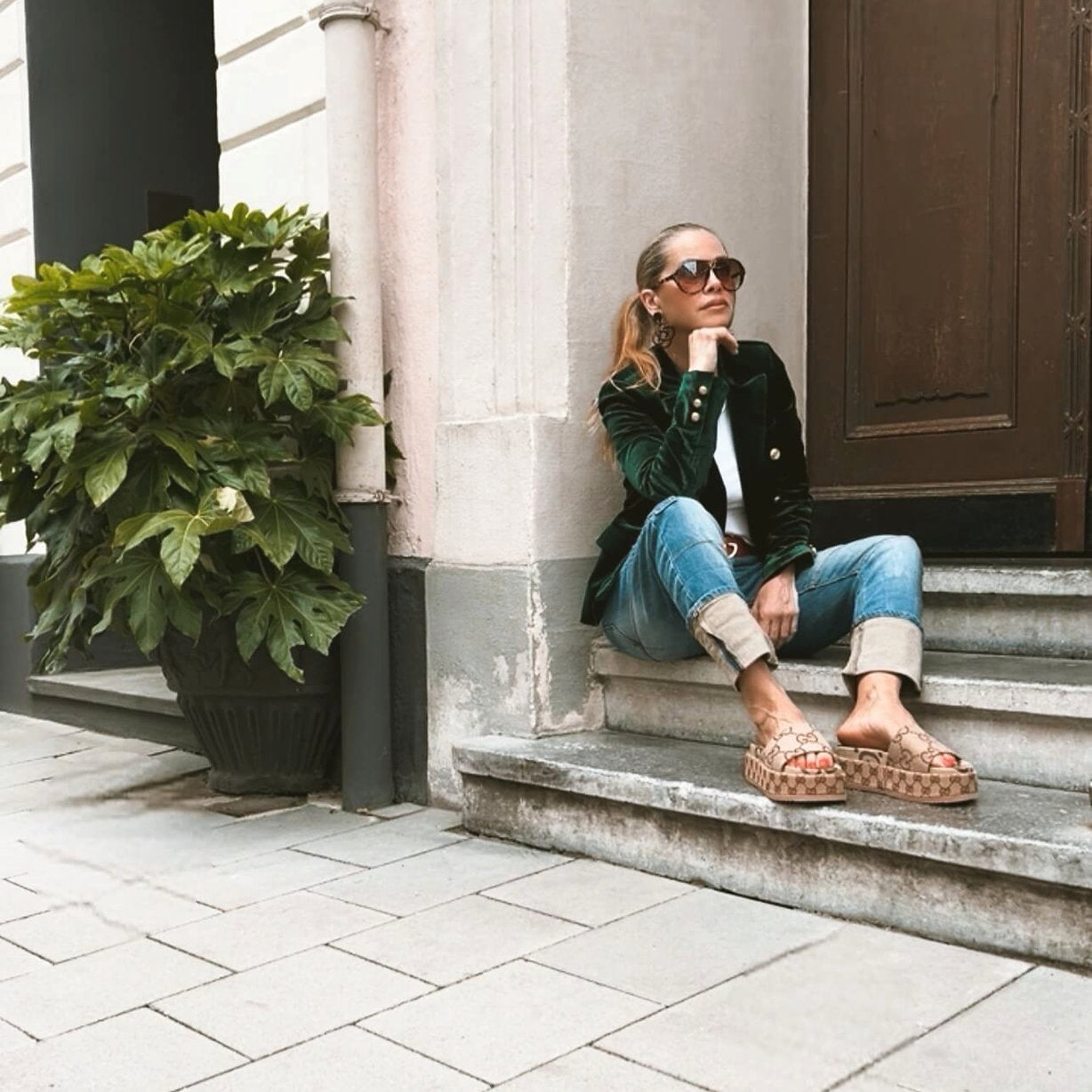 Model sitzt im CASAPARI® Samtblazer in Tannengrün. Weicher fallender Samt, goldene Knöpfe, entspannter Look mit eleganter Ausstrahlung.