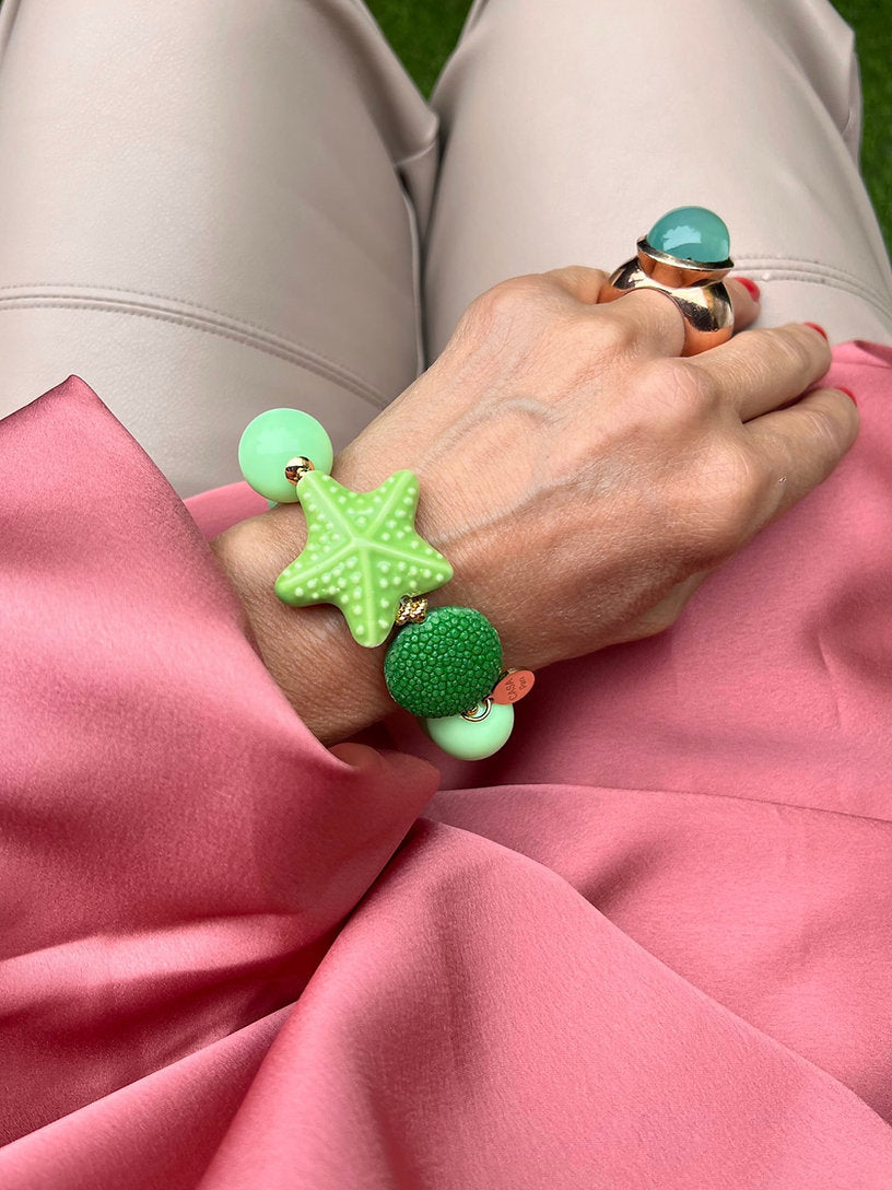Handgelenk mit grünen Armband aus großen Perlen, verziert mit einem grünen Seestern und einem runder Perle.