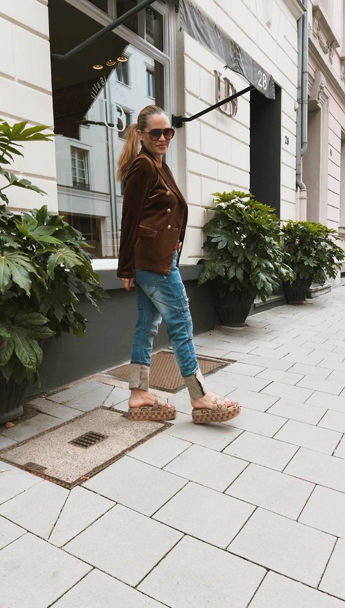 Seitliche Ansicht des CASAPARI® Samtblazer in Karamell. Weich fließender Samt, taillierte Silhouette, goldene Knöpfe vorne sichtbar.