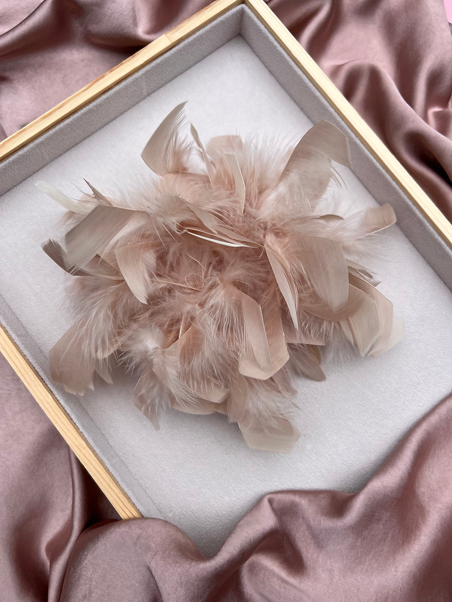 Federbrosche in Hellbeige auf Tablett mit Rosa Samt.