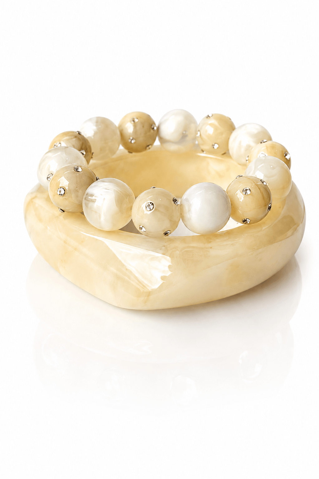 Marmorierter Resina-Armreif in Creamy Beige mit passendem elastischen Perlenarmband in Creme- und Sandtönen mit kleinen Strassdetails auf weißem Hintergrund.