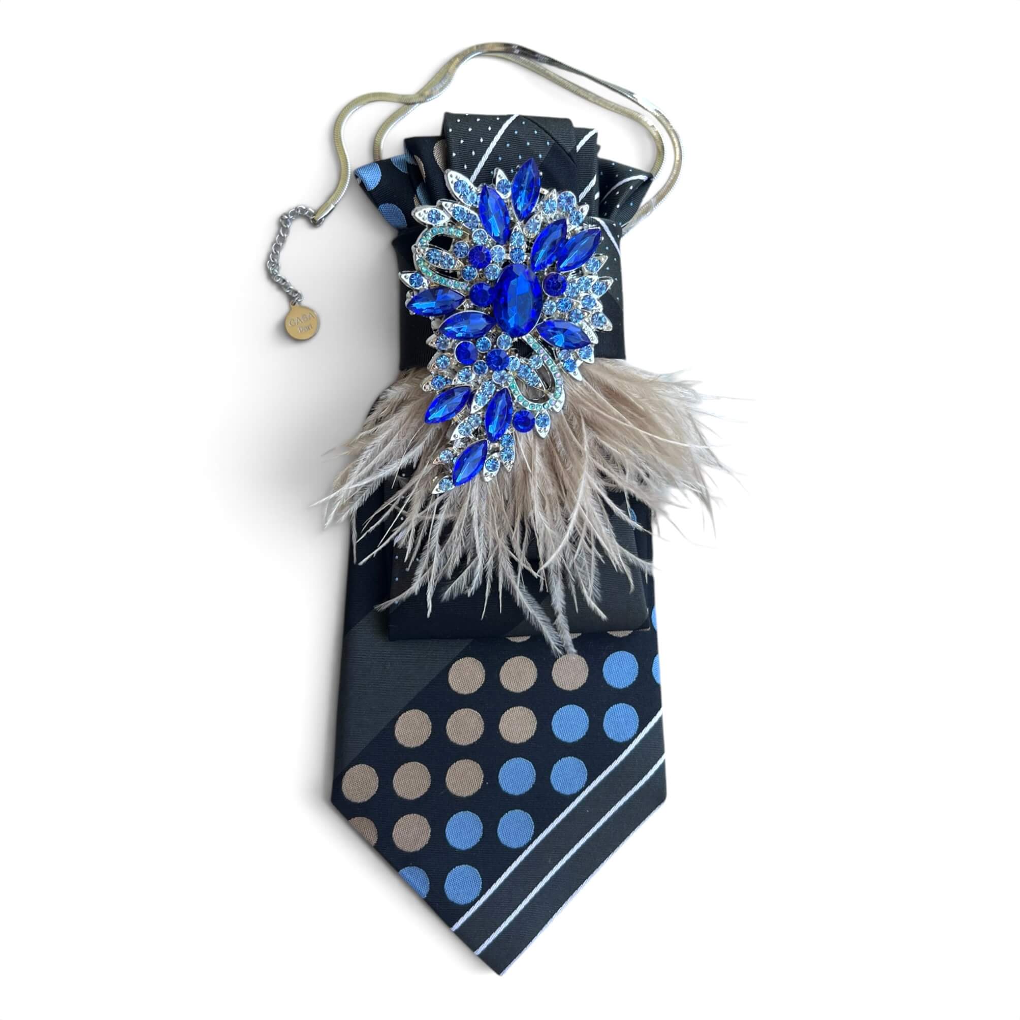 Graue Casapari Statement-Krawatte mit blau-taupefarbenem Muster, taupefarbenen Federn, royalblauer Schmuckbrosche und silberfarbener Kette