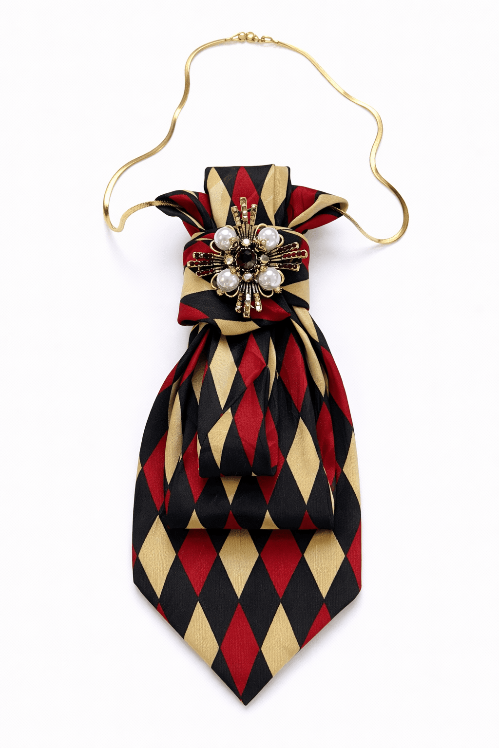 Krawatte mit Rautenmuster in Rot, Schwarz und Beige, kombiniert mit goldfarbener Kette und dekorativem Schmuckelement mit Perlen und Strass, frontal auf hellem Hintergrund