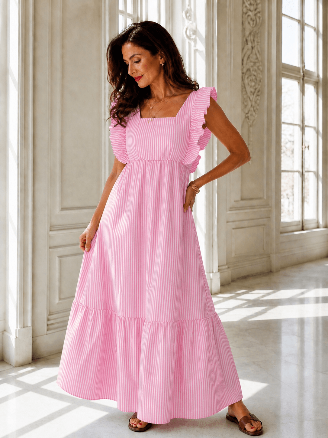 Frau trägt ein rosa-weiß gestreiftes Maxikleid mit Rüschenärmeln und weitem Rock in hellem Raum.