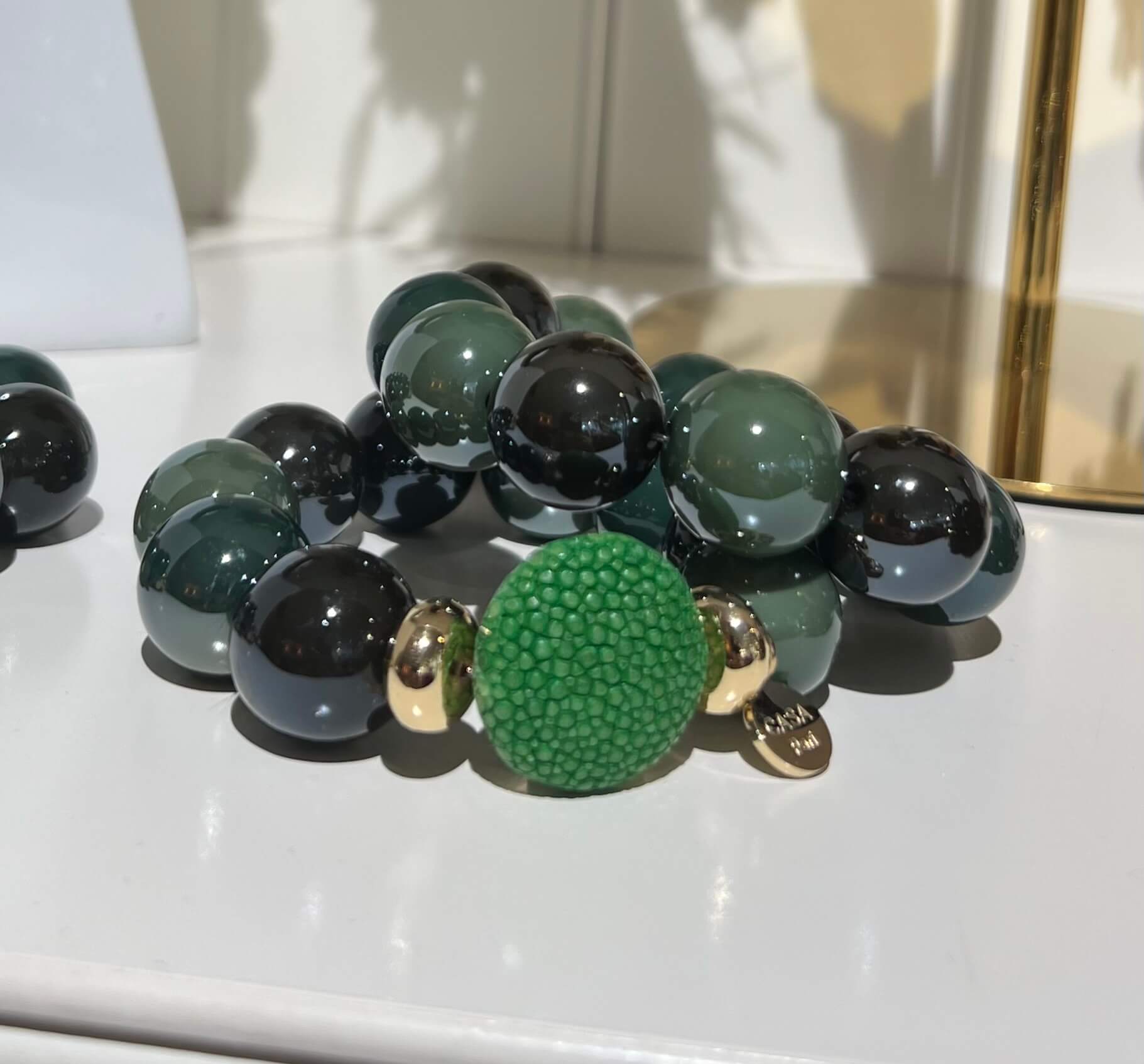 Grünes CASAPARI Armband mit glänzenden Resin-Perlen, grüner Rochenlederperle und goldfarbenen Details