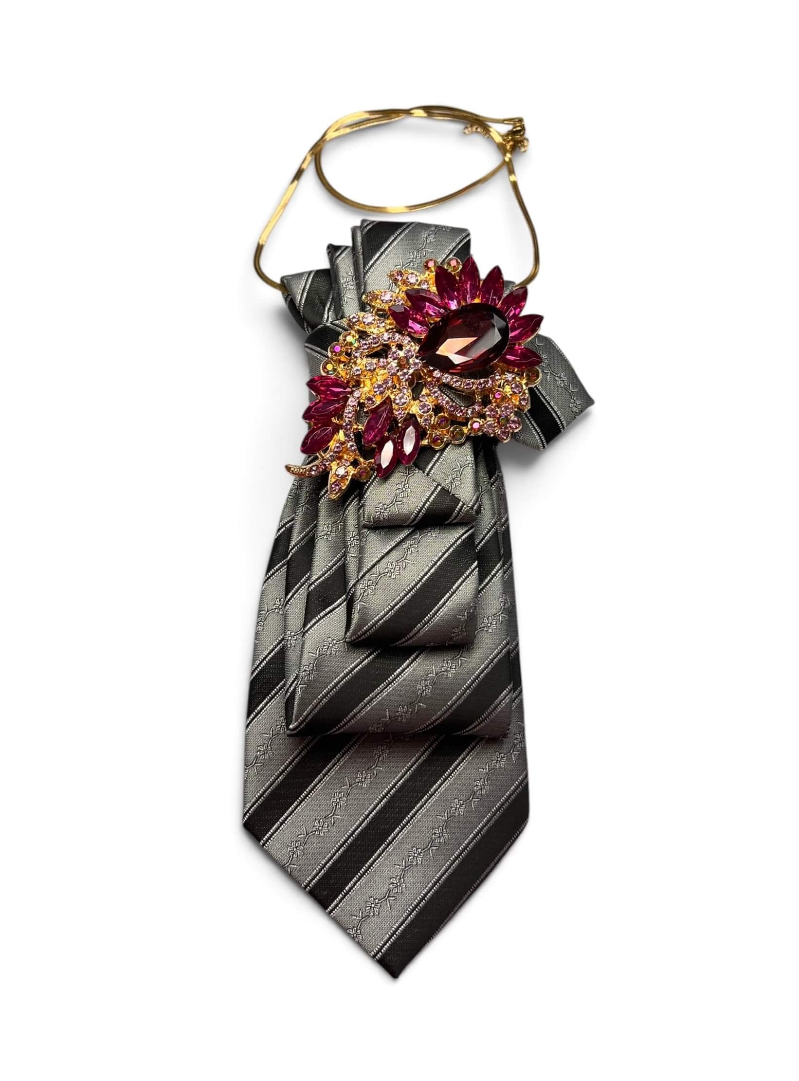 Vintage-Krawatte in Graphitgrau und Schwarz mit Streifenmuster, goldfarbener Halskette und Brosche mit bordeauxfarbenen und goldenen Schmucksteinen.