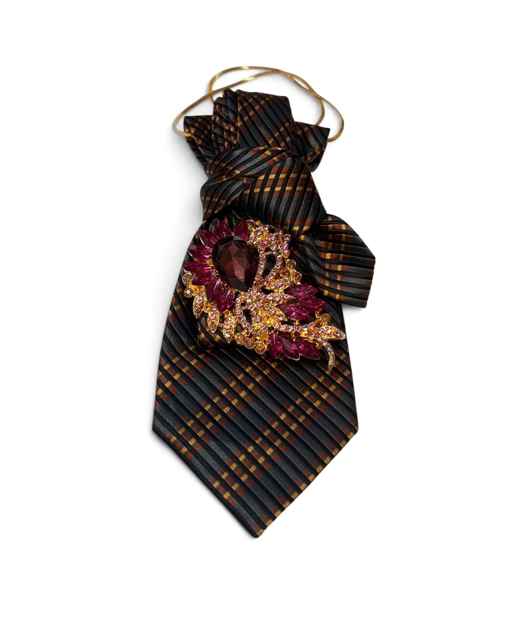 Dunkle Vintage-Krawatte in Schwarz mit feinem Streifenmuster in warmen Amber- und Kupfertönen, goldfarbener Halskette und dekorativer Schmuckbrosche.
