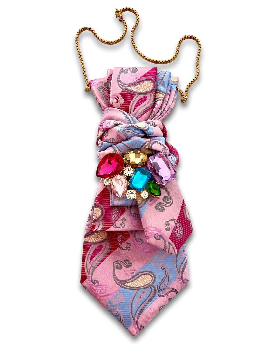 Rosafarbene Vintage-Krawatte mit Paisley-Muster, gebunden dargestellt, verziert mit einer Brosche aus bunten Steinen und goldfarbener Kette vor hellem Hintergrund.