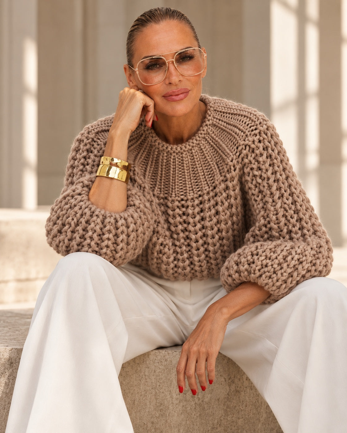 Model im taupefarbenen Chunky-Knit-Pullover mit weißer Marlenehose