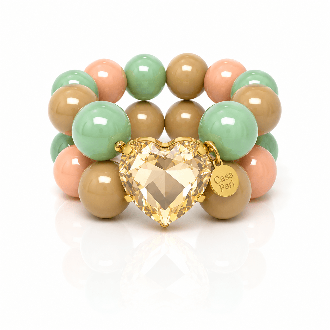 Crystal Heart Armband mit großen Perlen in Mintgrün, Apricot und Caramel sowie einem facettierten Herzanhänger in Goldton auf hellem Hintergrund.