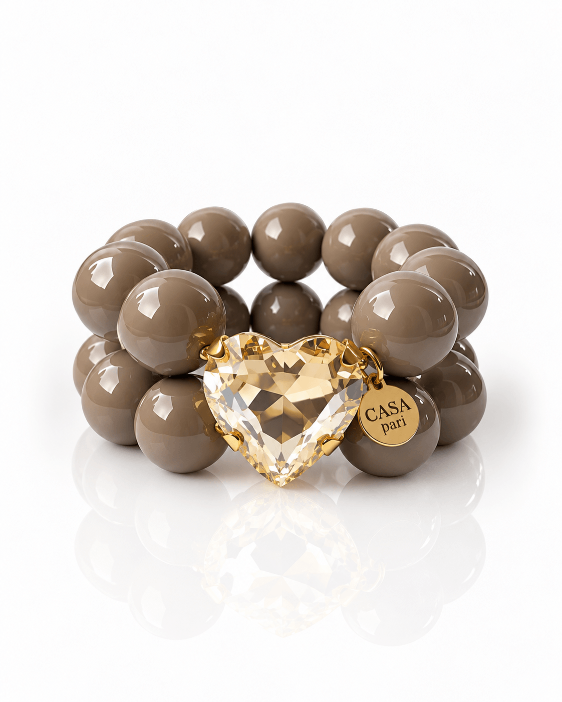 Armband aus großen taupefarbenen Perlen mit facettiertem Crystal Heart in Champagner und goldenem Casapari-Anhänger.