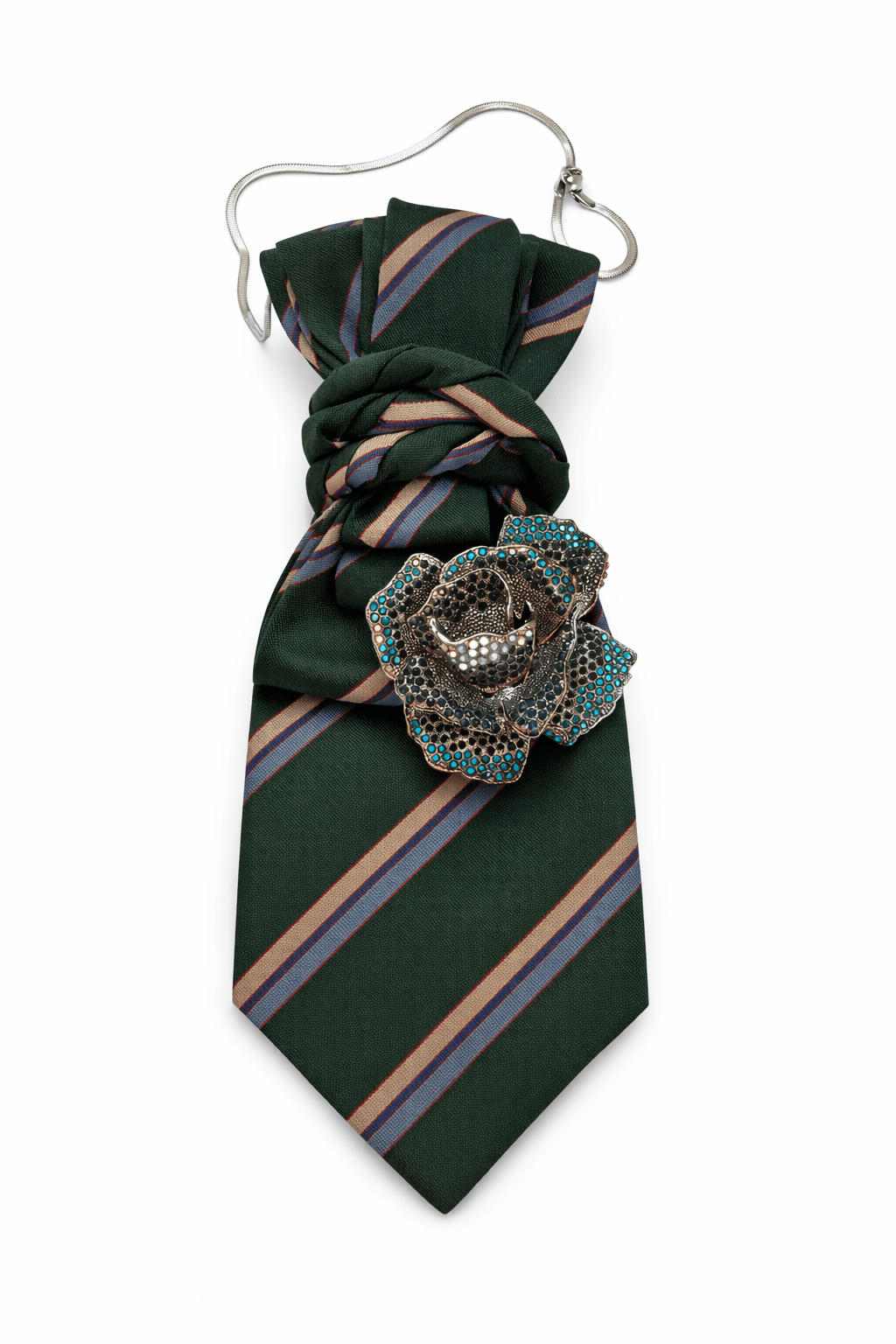 Grüne Krawatte mit diagonalen Streifen, silberfarbener Kette und großer Rosenbrosche mit blauen und dunklen Steinen, dekorativ gelegt auf hellem Hintergrund