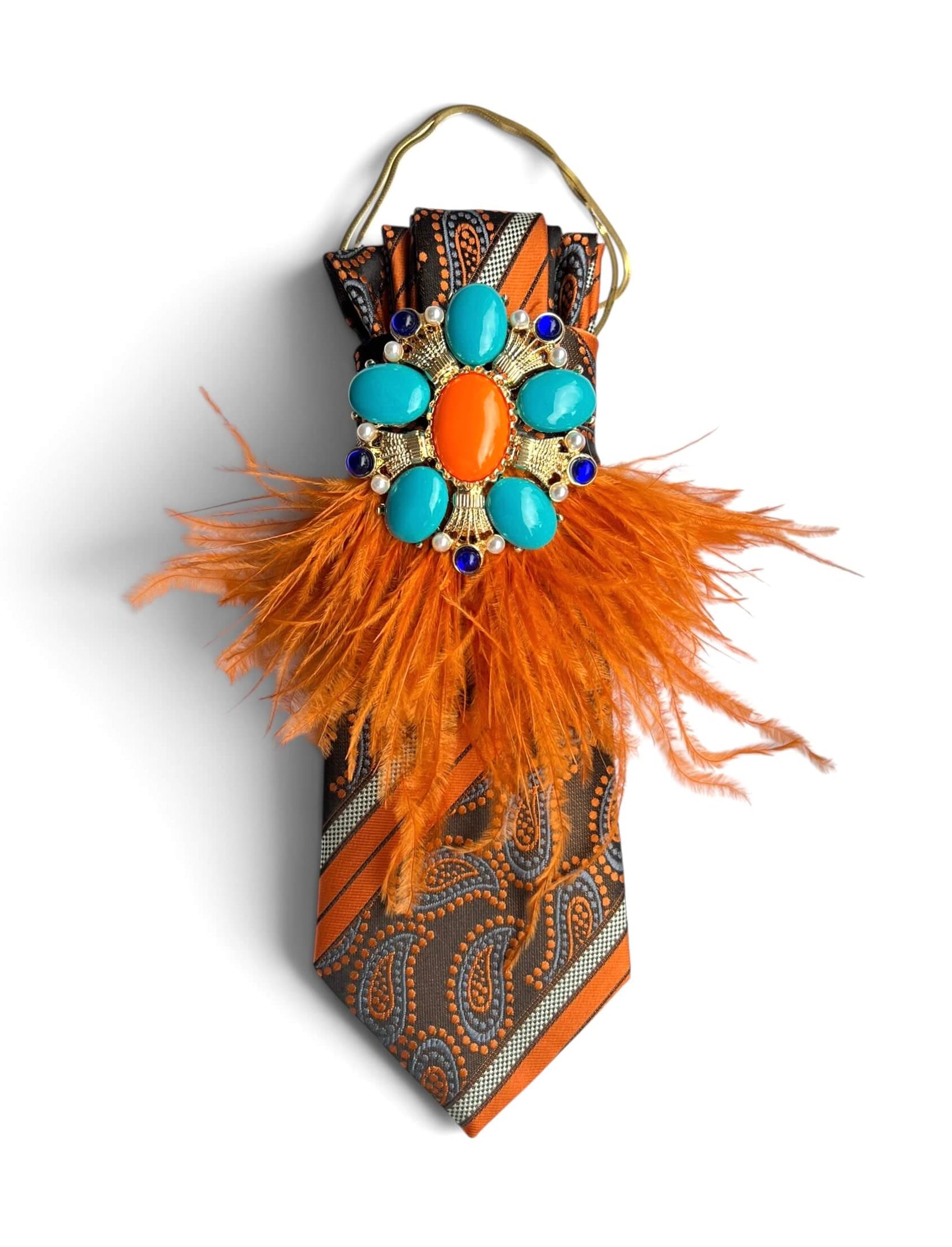 Vintage-Seidenkrawatte in Orange und Braun mit Paisleymuster, türkisfarbener Schmuckbrosche, orangefarbenen Federn und goldfarbener Kette.