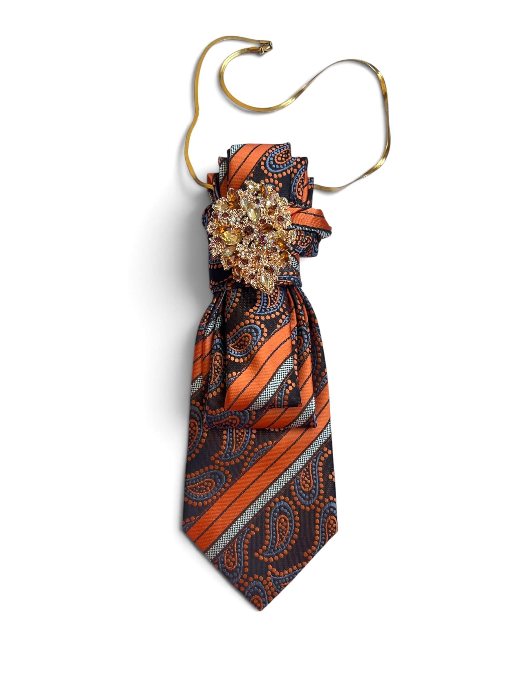 Krawatte in Braun und Cognac mit Muster und goldfarbener Brosche auf weißem Hintergrund