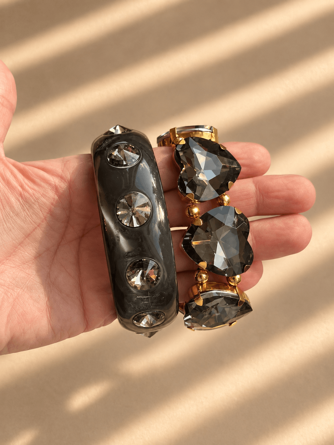 Midnight Smoke Schmuckset in der Hand mit rauchgrauem Bangle und The Grand One Armband aus facettierten Kristallherzen