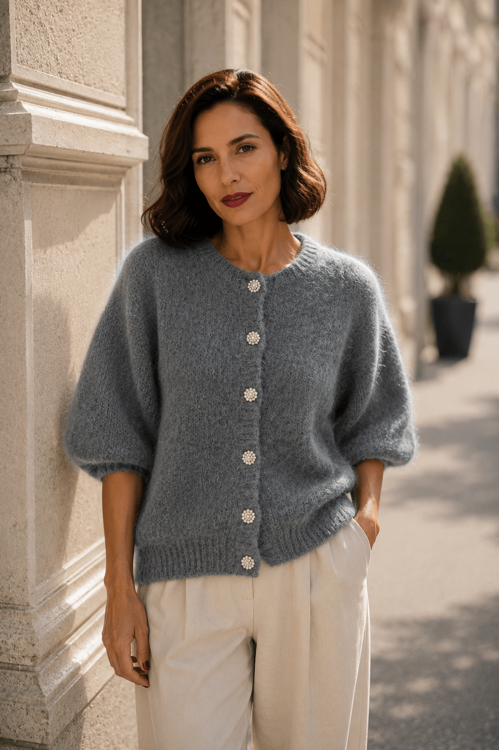 Grauer Milano Kid Mohair Cardigan mit funkelnden Schmuckknöpfen und Dreiviertelärmeln, kombiniert mit einer cremefarbenen Marlenehose.