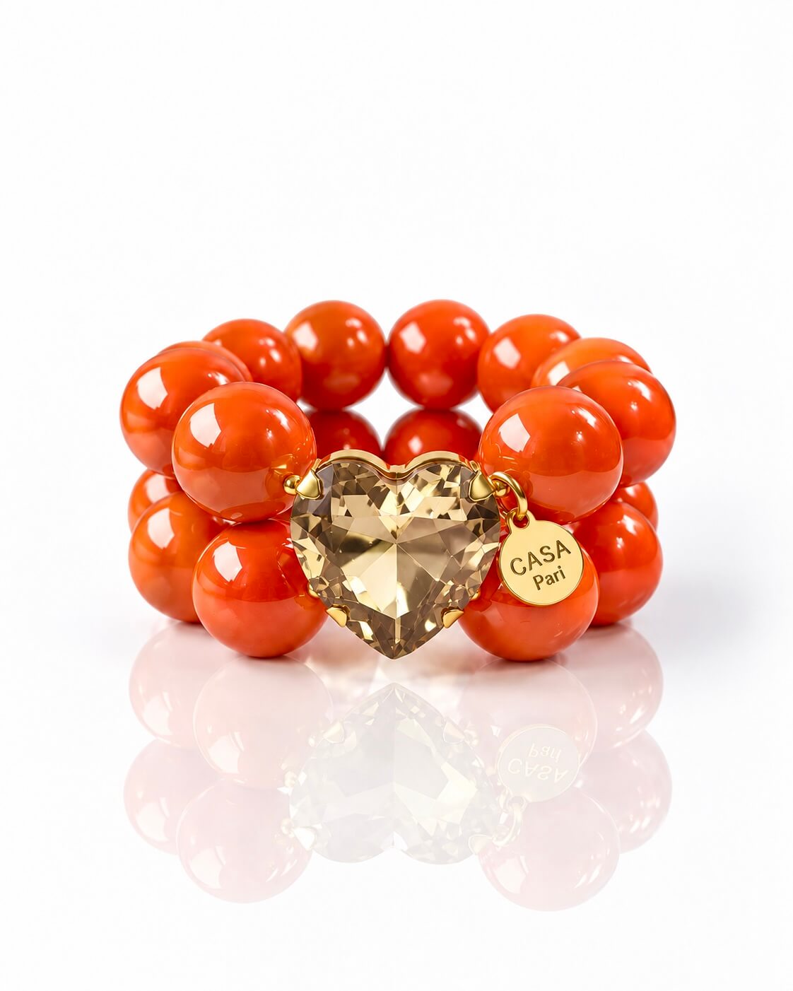 Orangefarbenes doppel reges Armband mit goldenem Herz auf weißem Hintergrund fotografiert