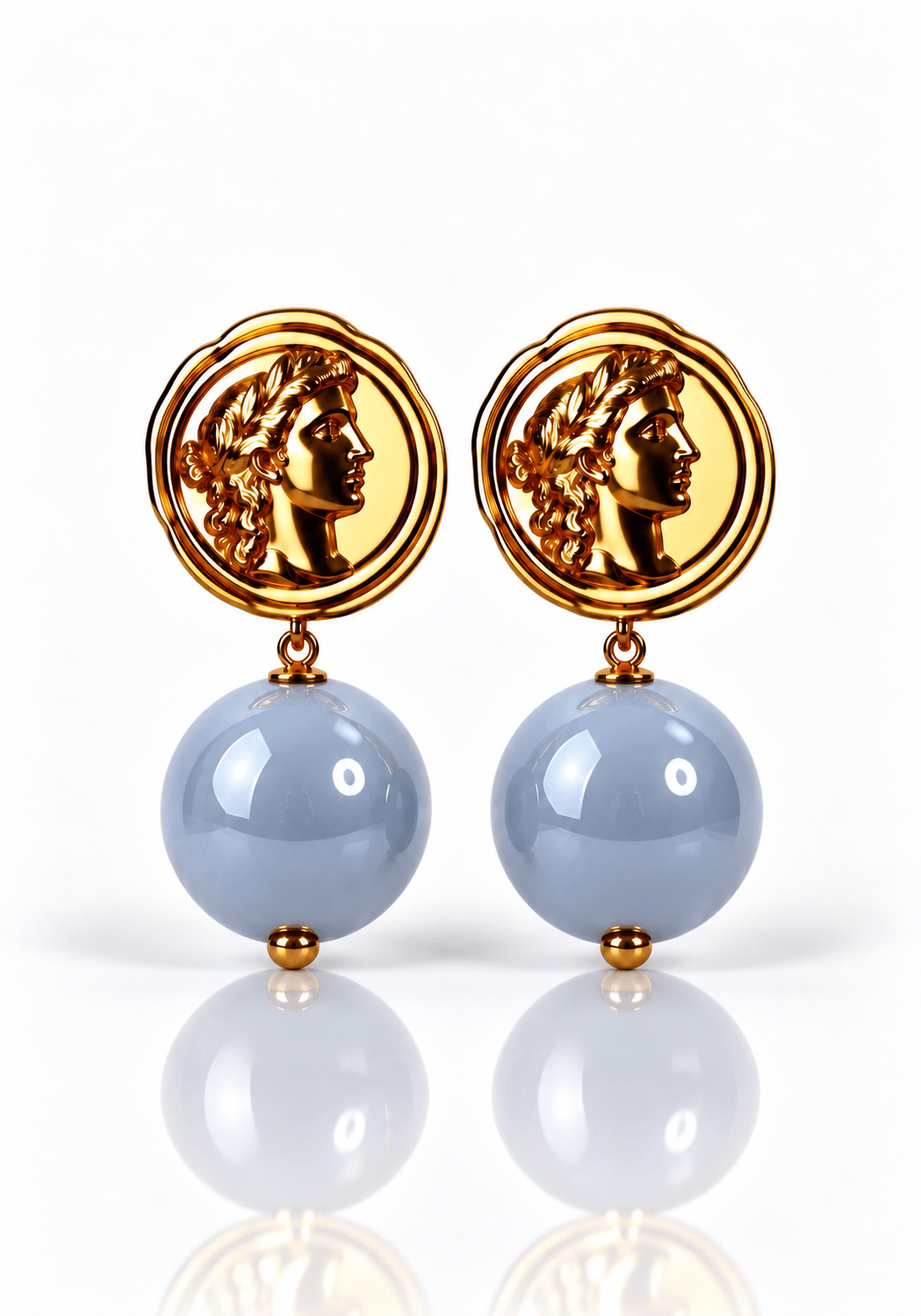 Goldfarbene Roma Ohrringe von Casapari mit runden hellblauen Resin-Perlen und dekorativem Münzmotiv.