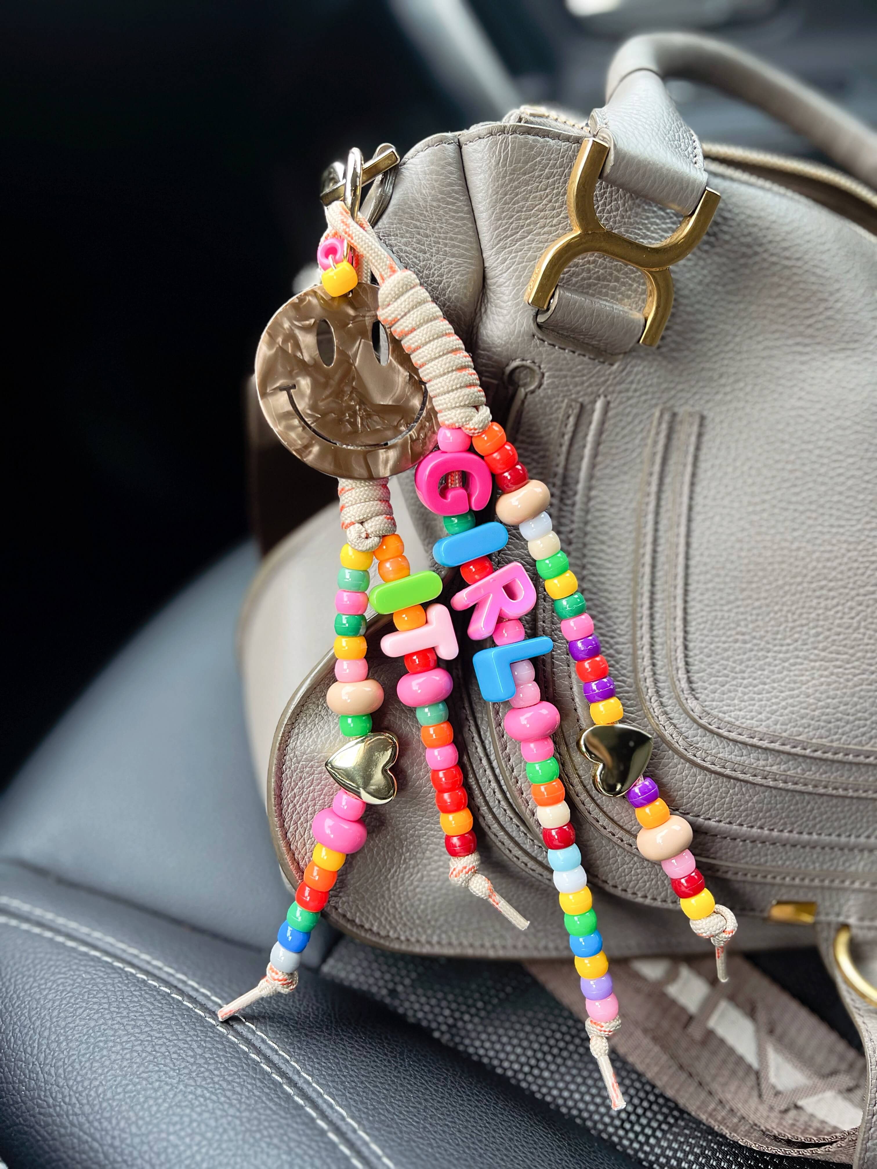 Bunter CASAPARI Taschenanhänger Charming It-Girl mit schimmerndem Smiley, farbigen Perlen und goldfarbenen Herzen an einer Handtasche