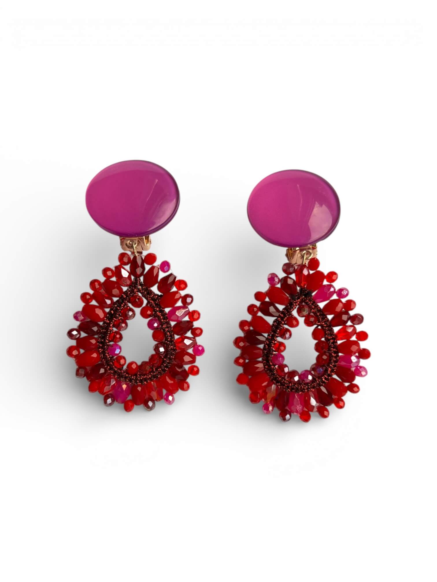 Garne-Ohrringe in Rot mit pinkem Cabochon und tropfenförmigem Anhänger aus facettierten Glasperlen vor hellem Hintergrund.