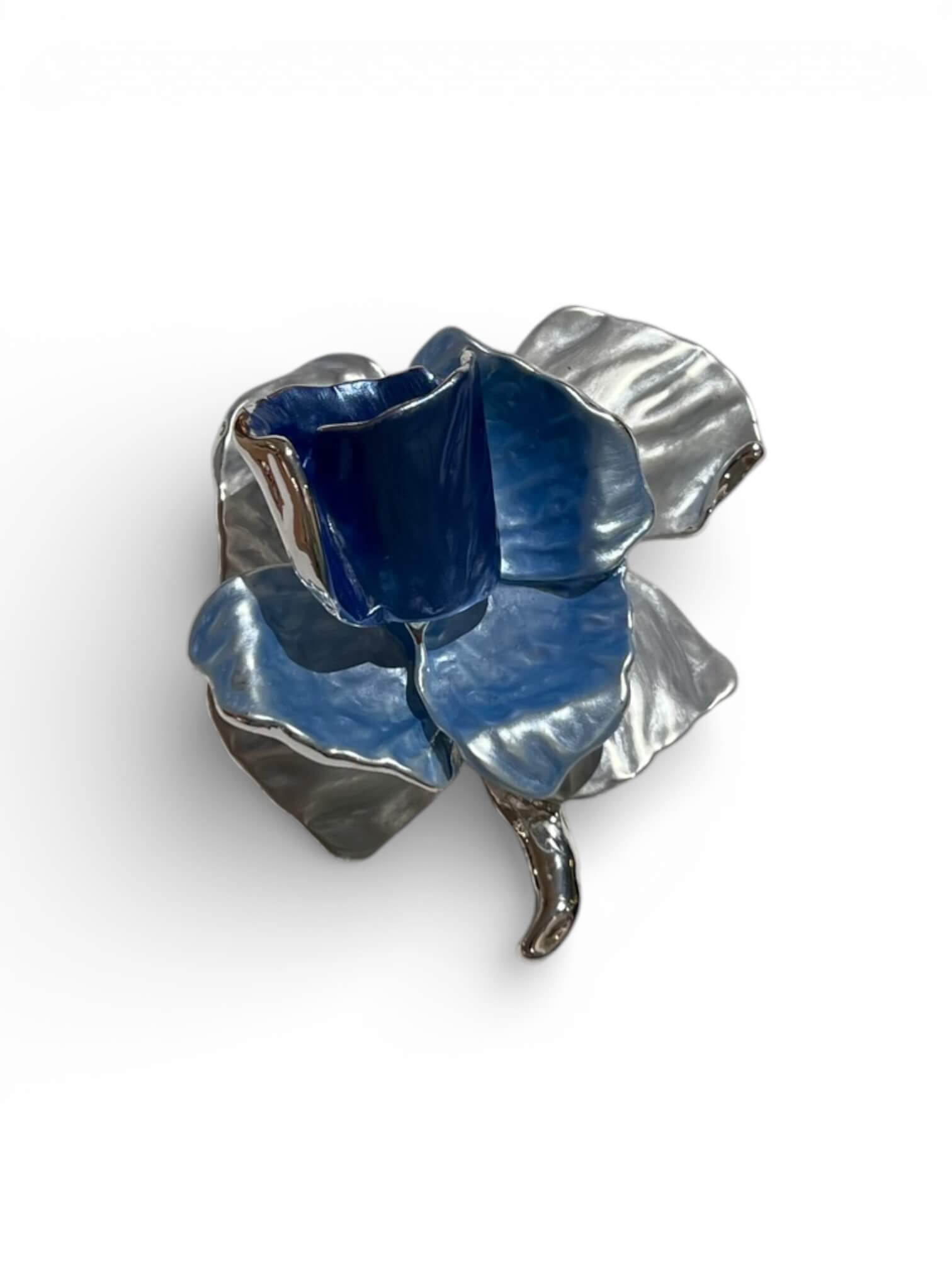 Magnetbrosche in Form einer stilisierten Rose in Blau mit silberfarbenen Stiel, freigestellt vor hellem Hintergrund.