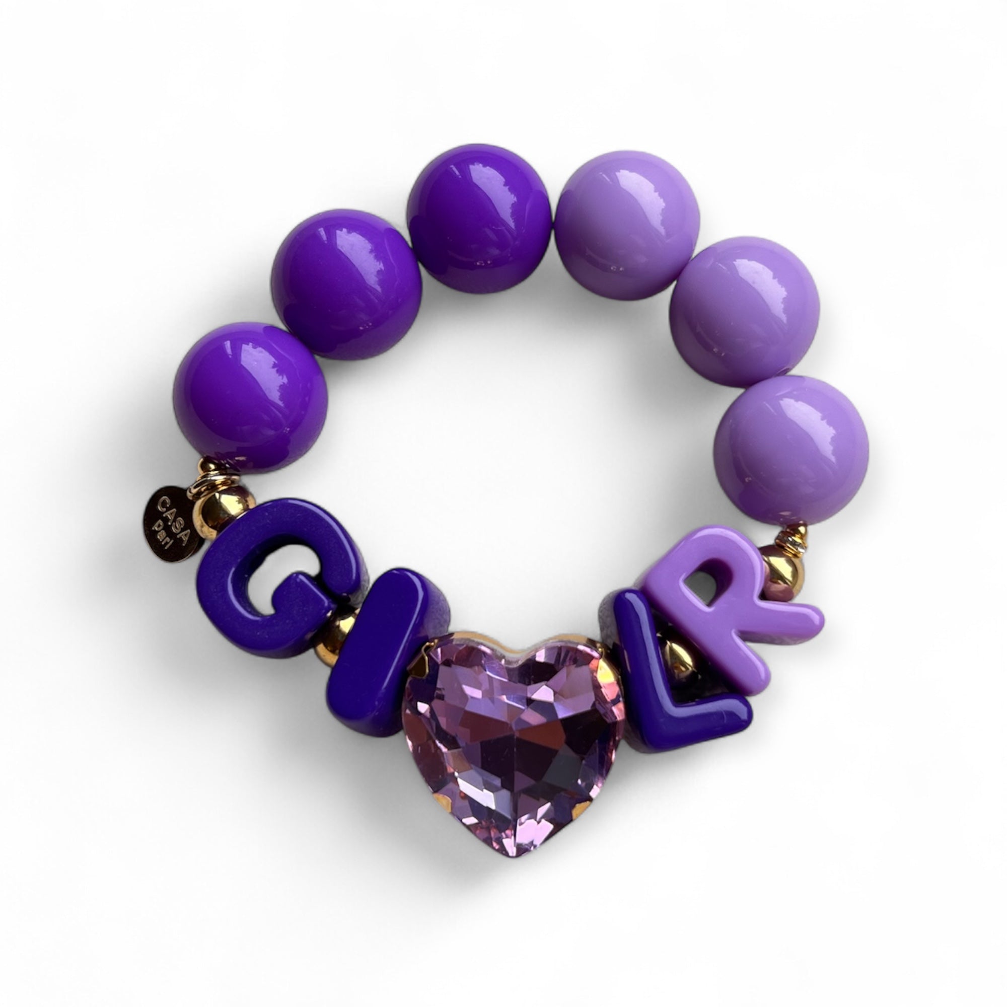 Lila Armband aus großen, glänzenden Perlen mit goldfarbenen Details. In der Mitte Buchstaben, die das Wort GIRL bilden, und ein funkelnder, herzförmiger Stein in Amethyst Lila. 