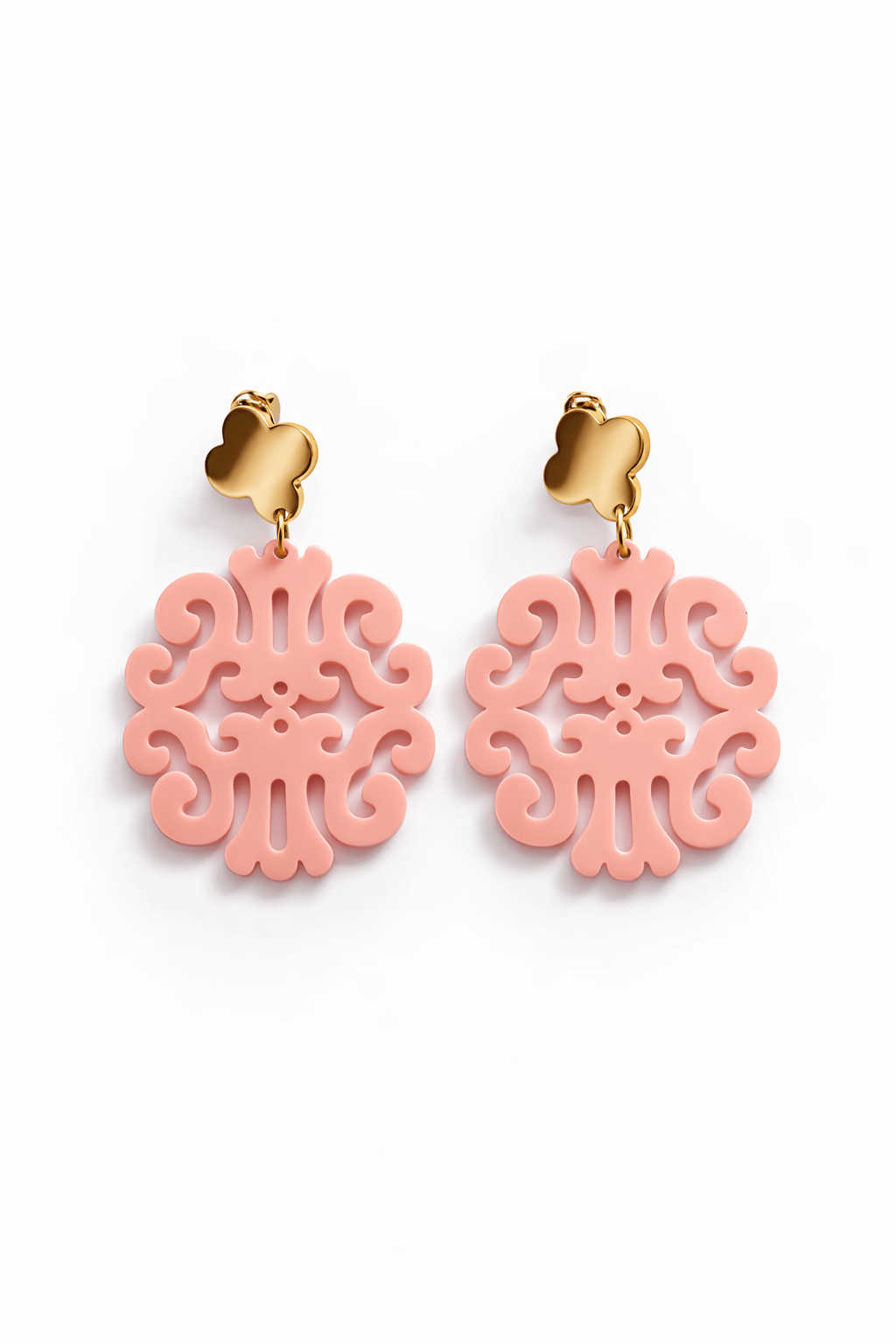 Paar hängende Ohrringe mit goldfarbenem Kleeblatt-Stecker und rosa ornamental durchbrochenem Anhänger vor weißem Hintergrund.
