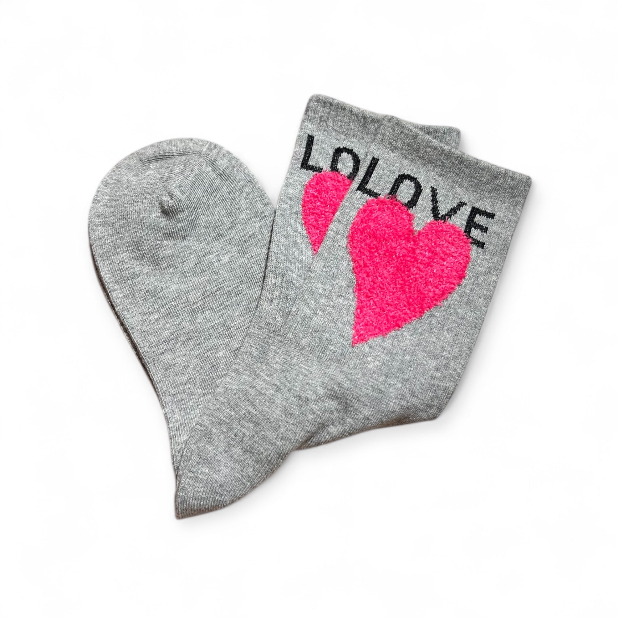 Graue Strümpfe mit pinkfarbenem Herzmotiv und dem Schriftzug LOVE am Bund. Flauschige Struktur auf dem Herz, flach liegend auf weißem Hintergrund.