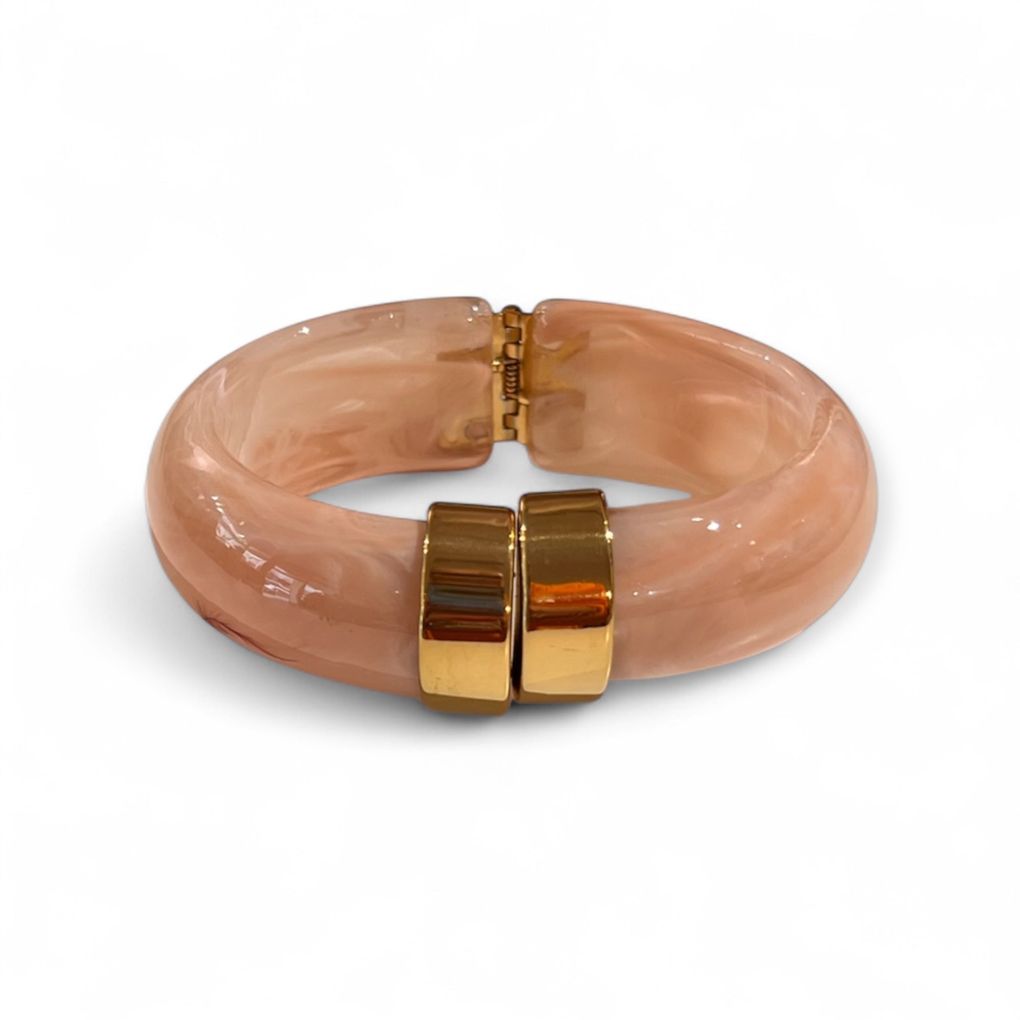 Klapp Armreif in rosa mit goldenen Details. Auf weißem Hintergrund fotografiert.